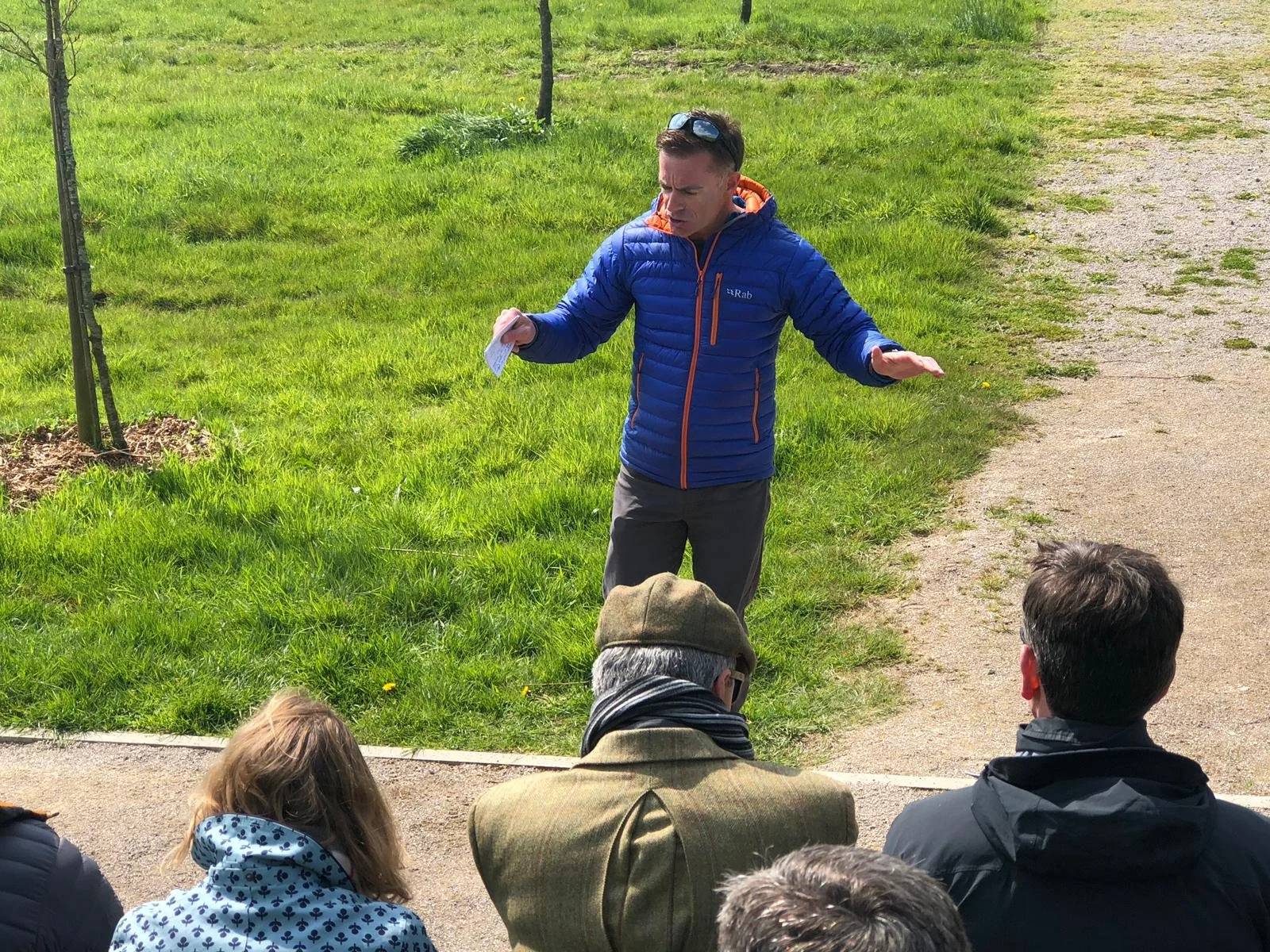 Group of women gathered around a table making holiday wreaths with greenery, ribbons, and decorative supplies in a cozy, well-lit room.