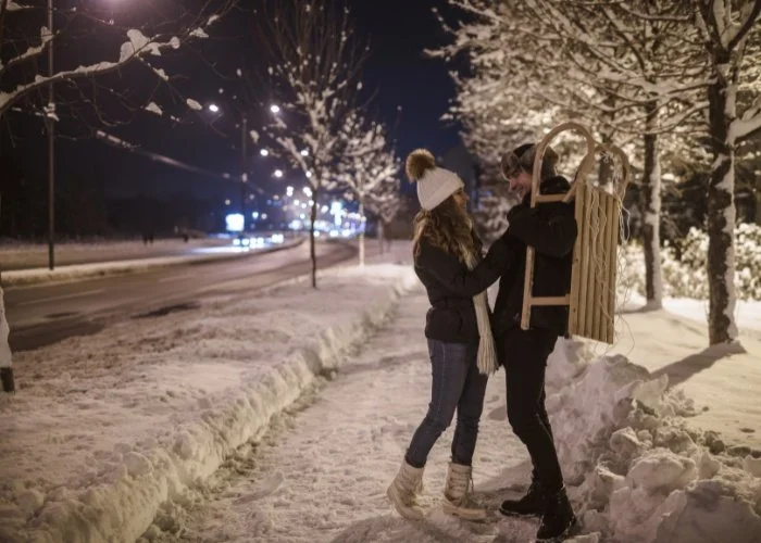 Couple walking on snowy Lake Michigan beach at sunset – romantic winter date in Michigan.