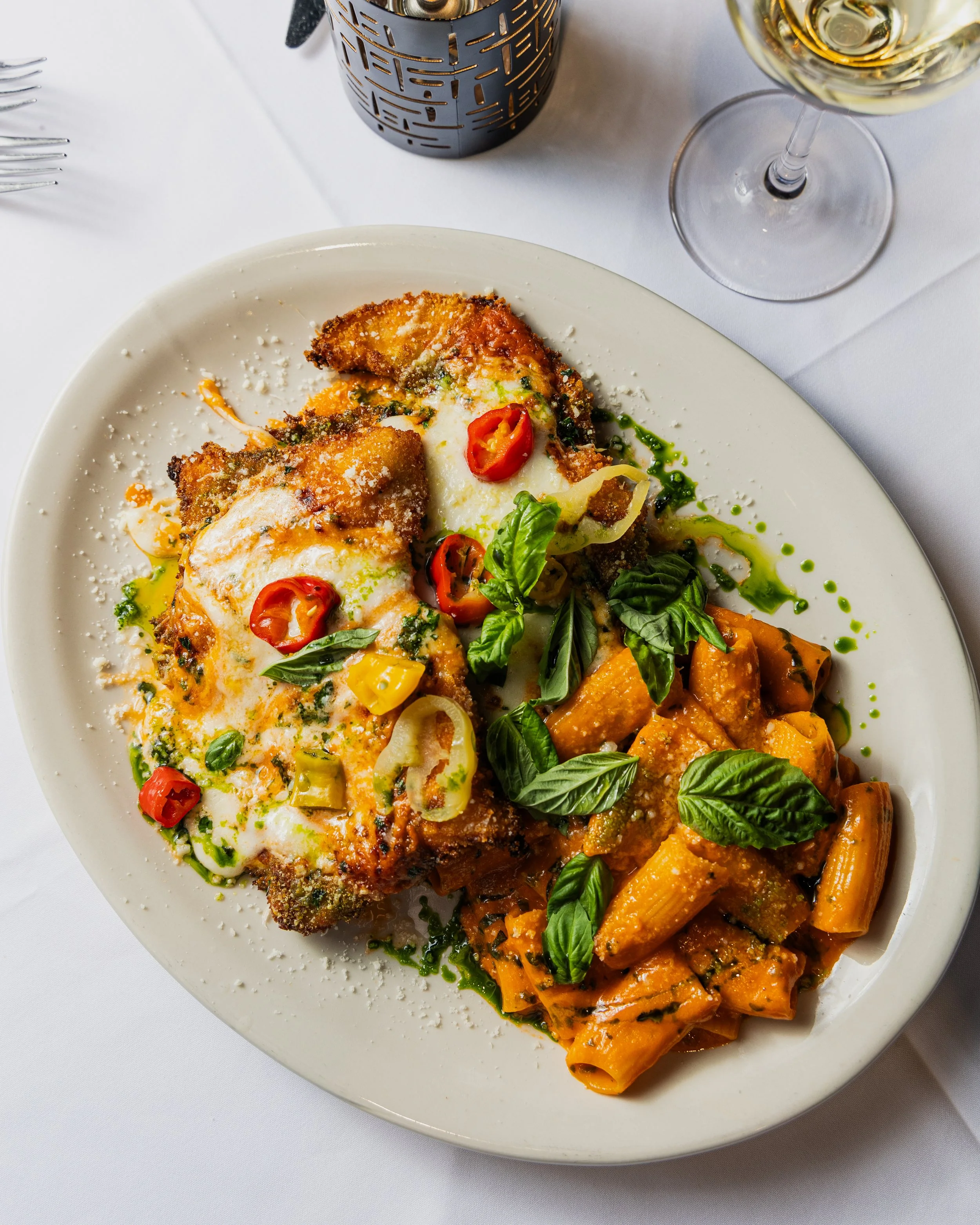 A gourmet dish featuring chicken parmesan and vodka rigatoni plated beautifully. 