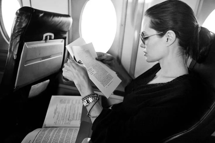 Angelina Jolie reading documents while seated on an airplane.