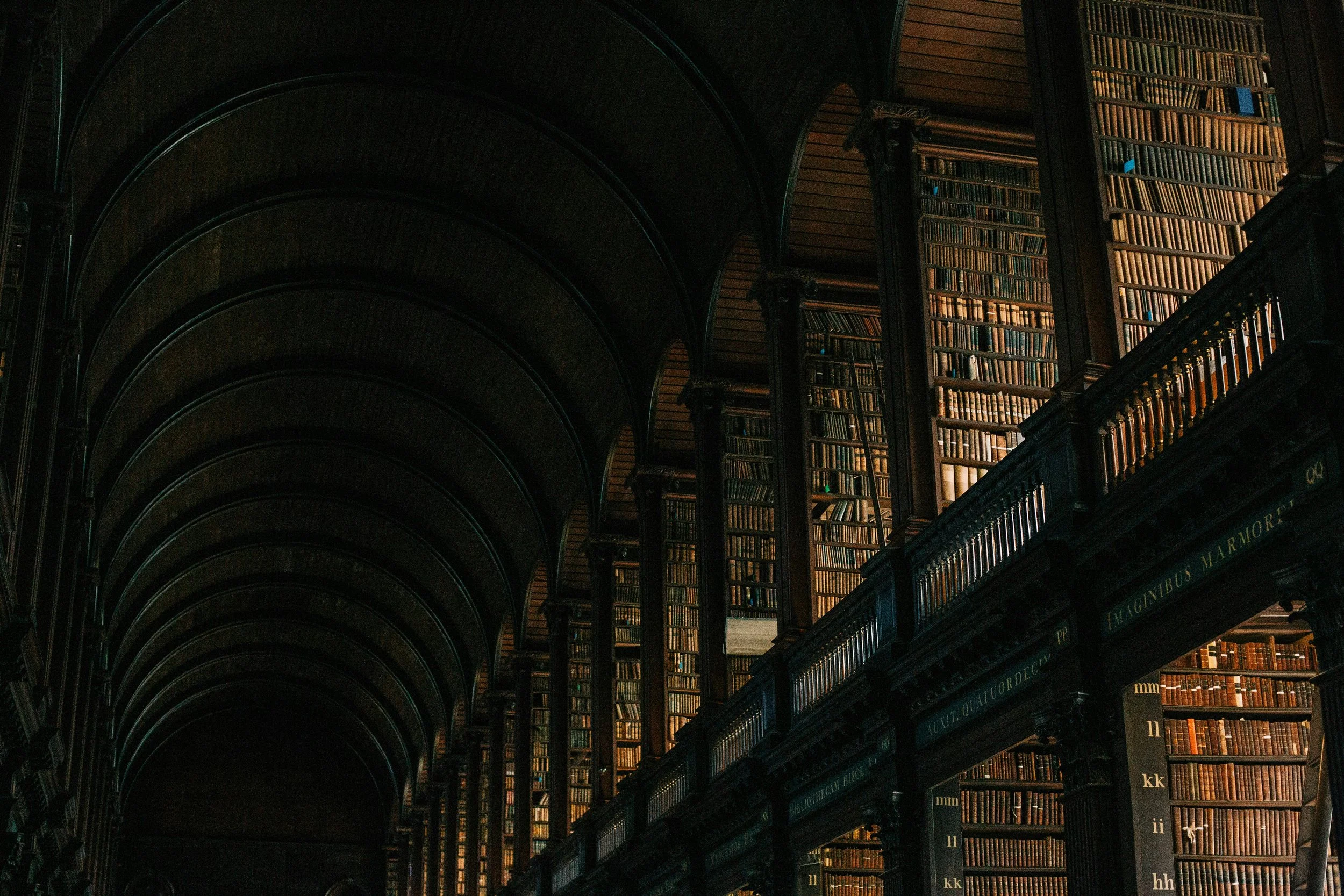 Interior of a grand historic library with towering wooden bookshelves and arched ceilings lined with books.