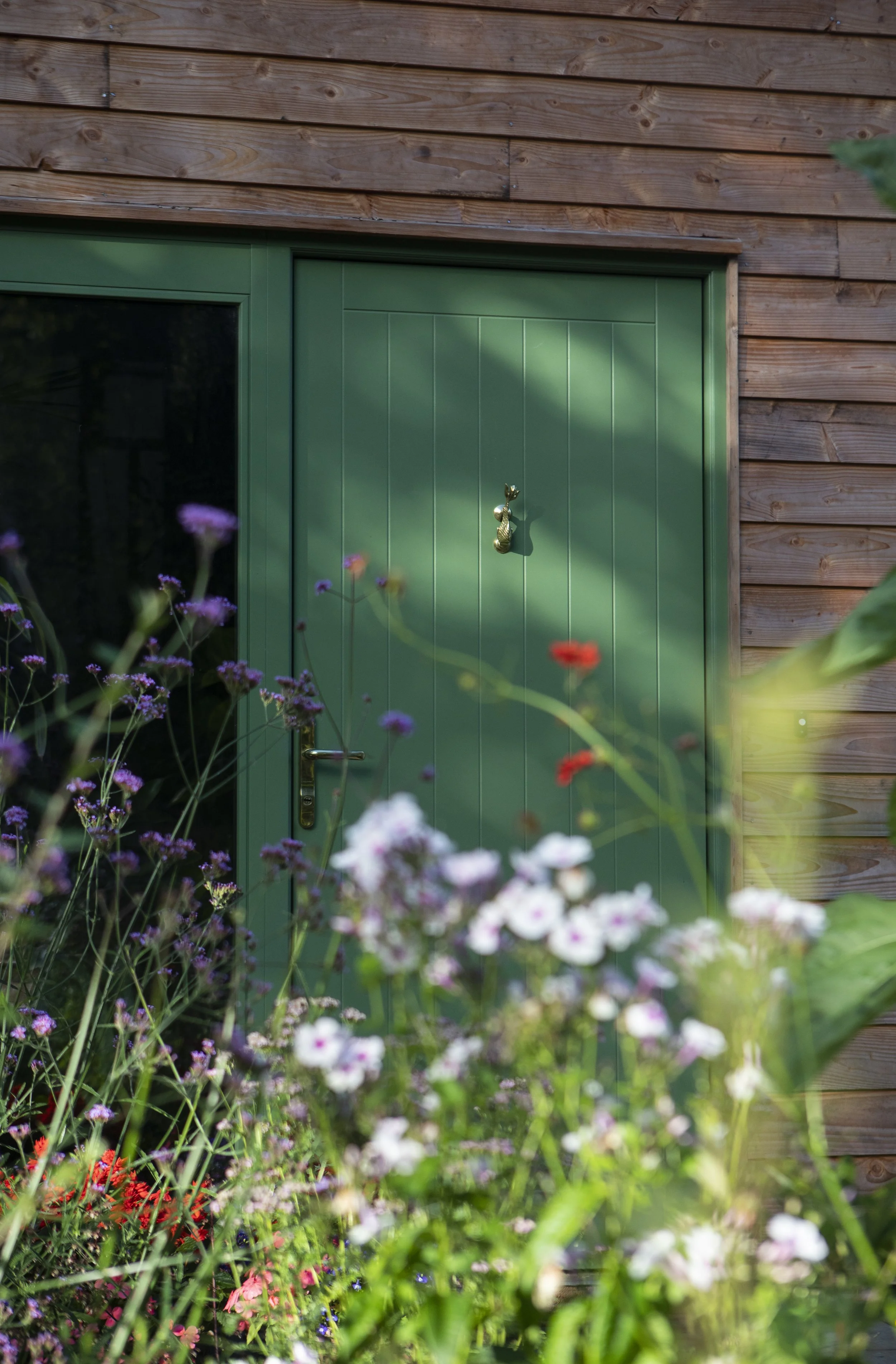 View of a green door beyond a flowering meadow