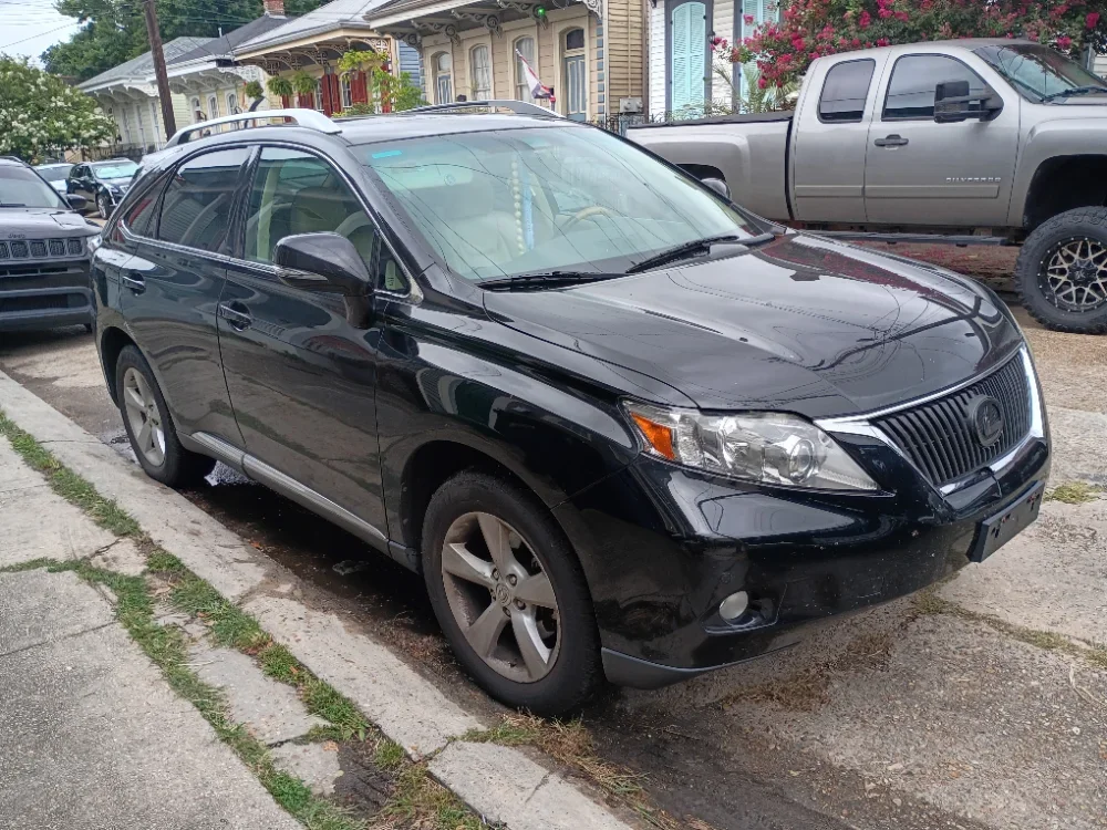 A black crossover SUV parked on a residential street, with houses and other parked vehicles in the background.