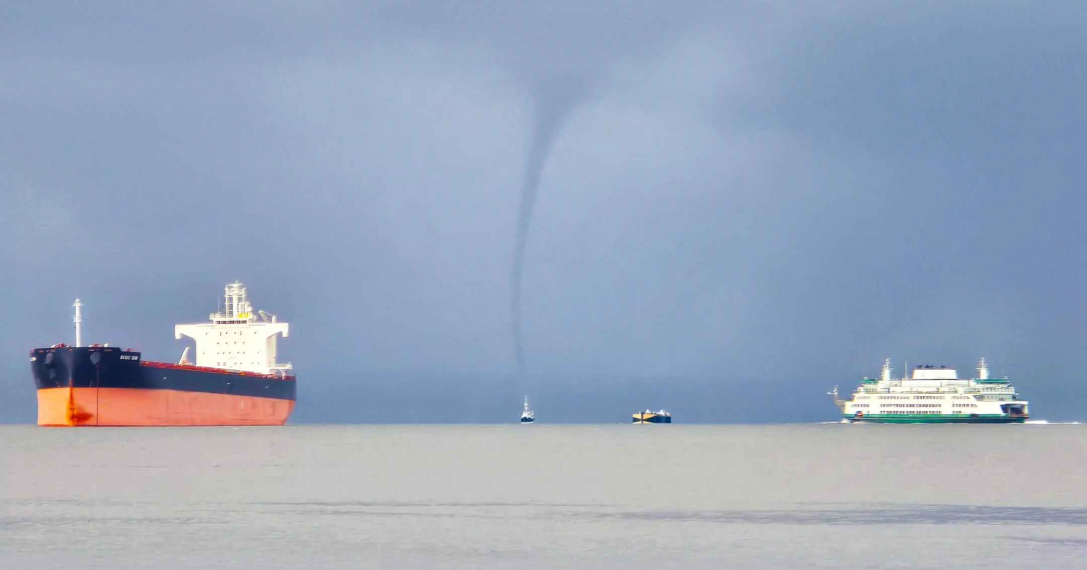 A rare waterspout appeared last week as part of a storm cell in Elliot Bay just off downtown Seattle. At the center of the photo, the Vane Brothers tug SEVERN has the barge Double Skin 505 astern on a towing line. A Washington State Ferry boat is see
