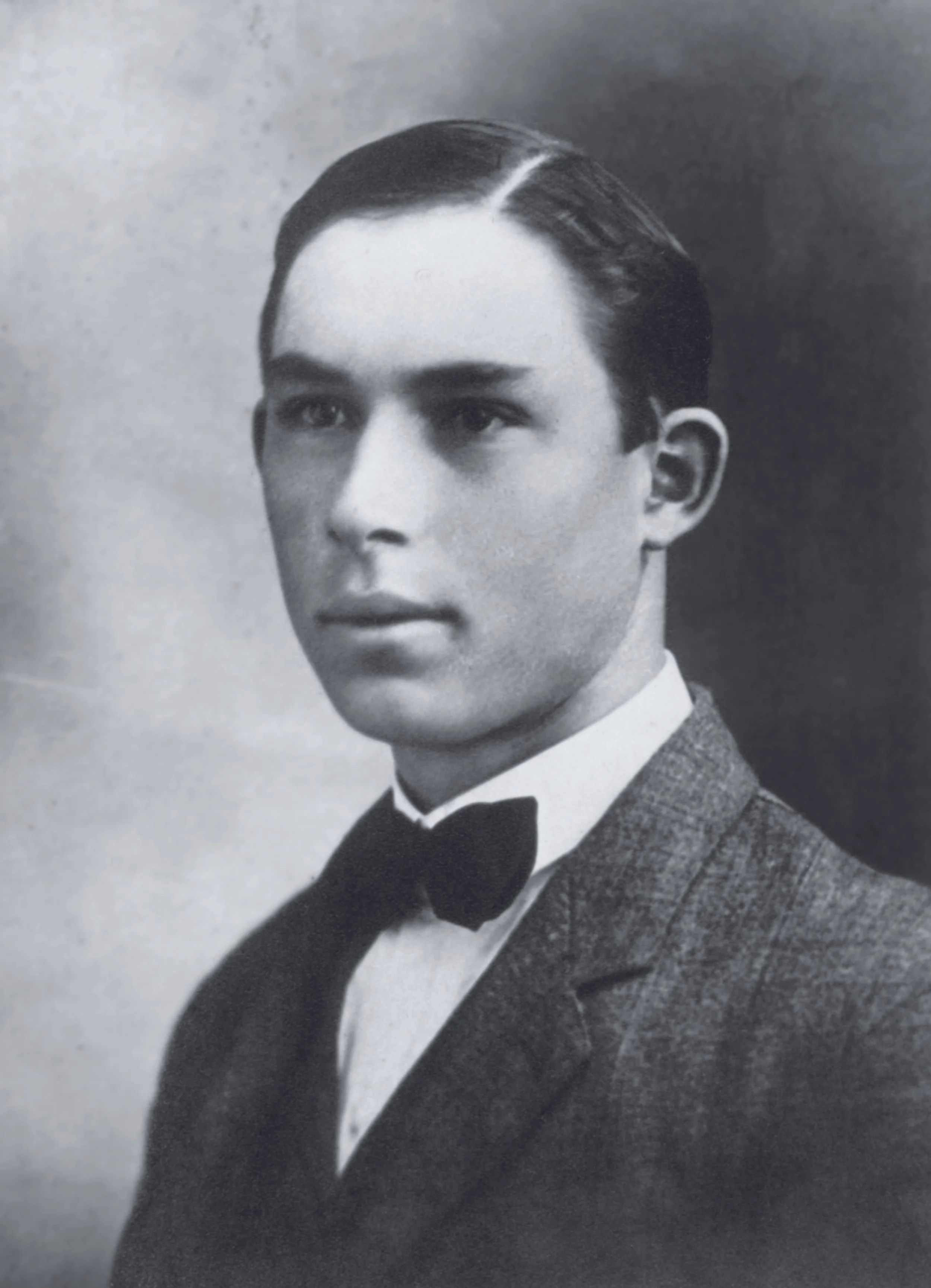 Black and white portrait of a young man in a suit with a bow tie, looking slightly to the side.