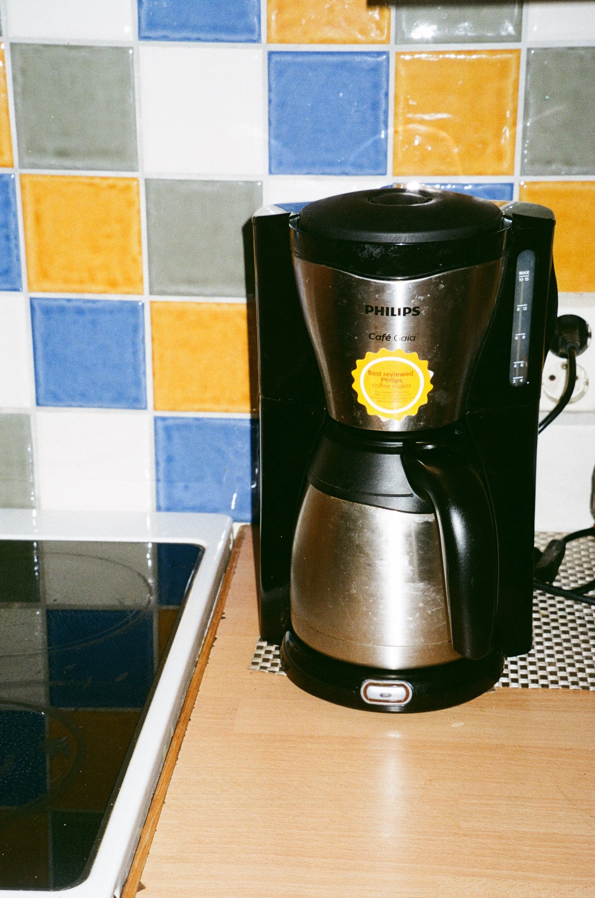 innzoomet fotografi av kaffetrakter på benk med fargede fliser bak