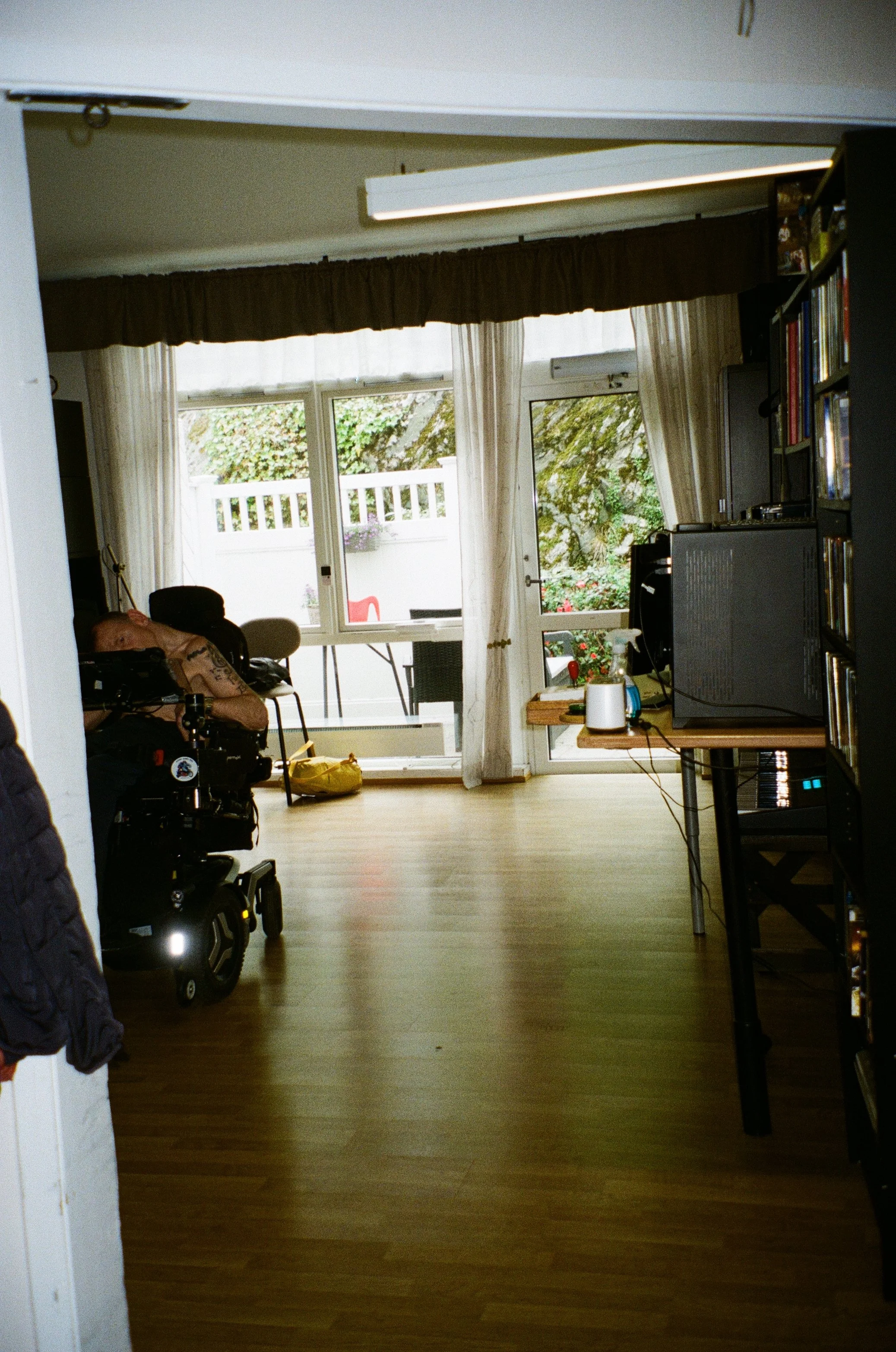 foto seende inn mot vindu igjennom en åpning med karmer. person til venstre.