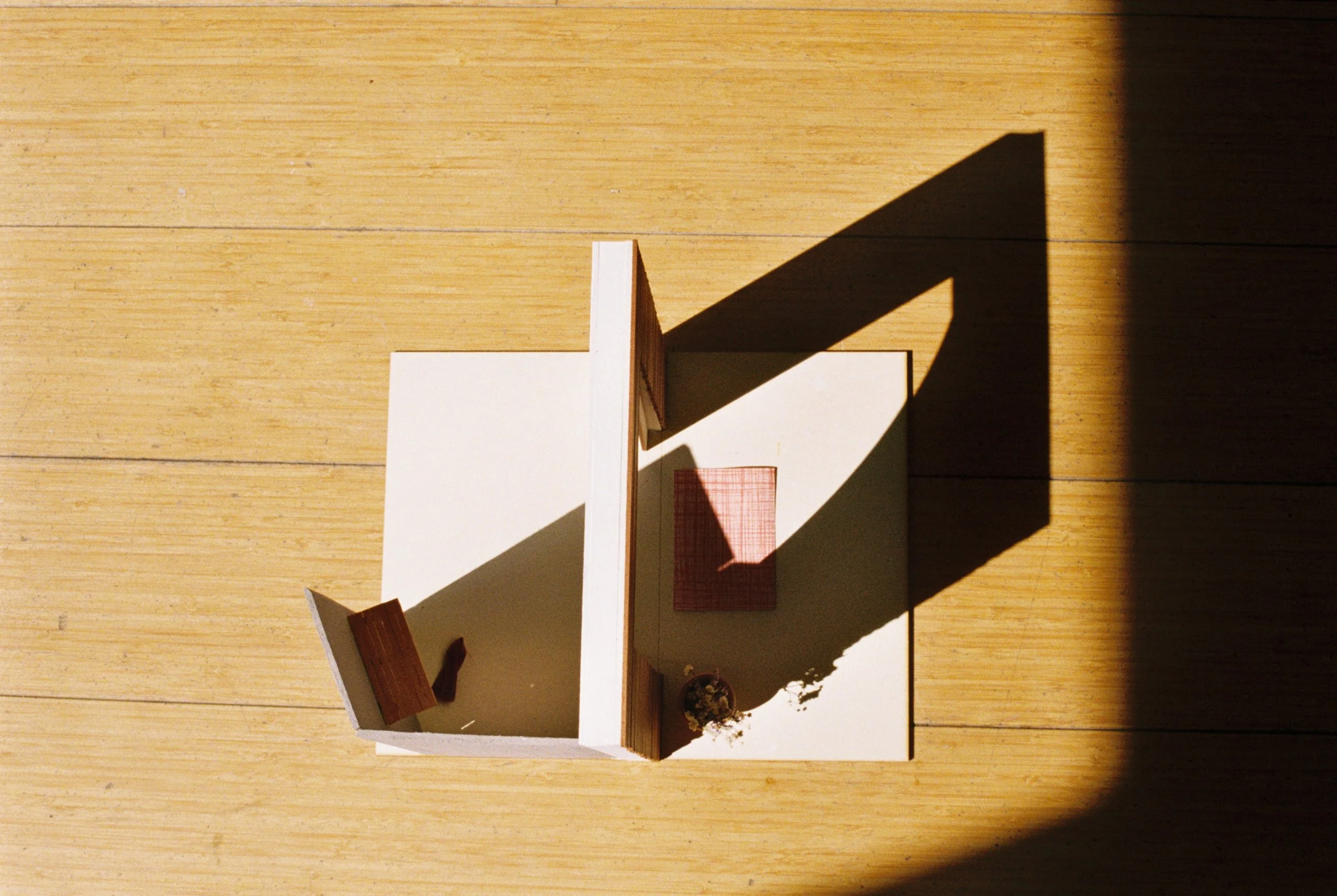 modell av em dør sett ovenifra på tregulv. Lyset kaster skygge av dørkarmene og åpningen lyser opp.