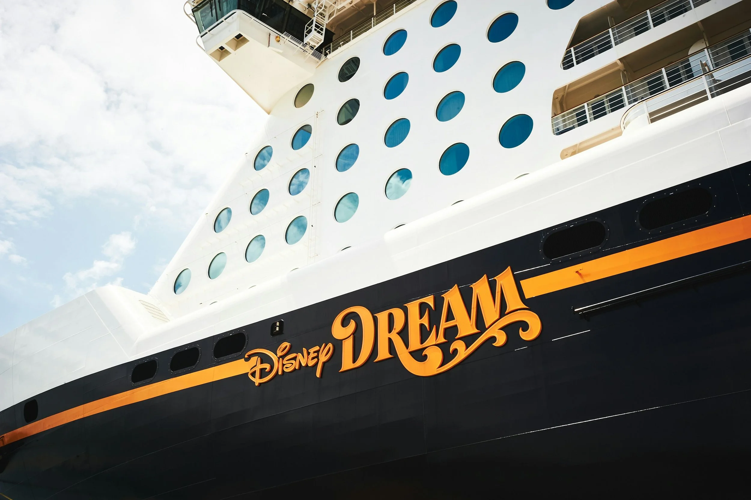 Close-up of a cruise ship with the Disney Cruise ship Dream, showing portholes, decks, and a blue sky background.