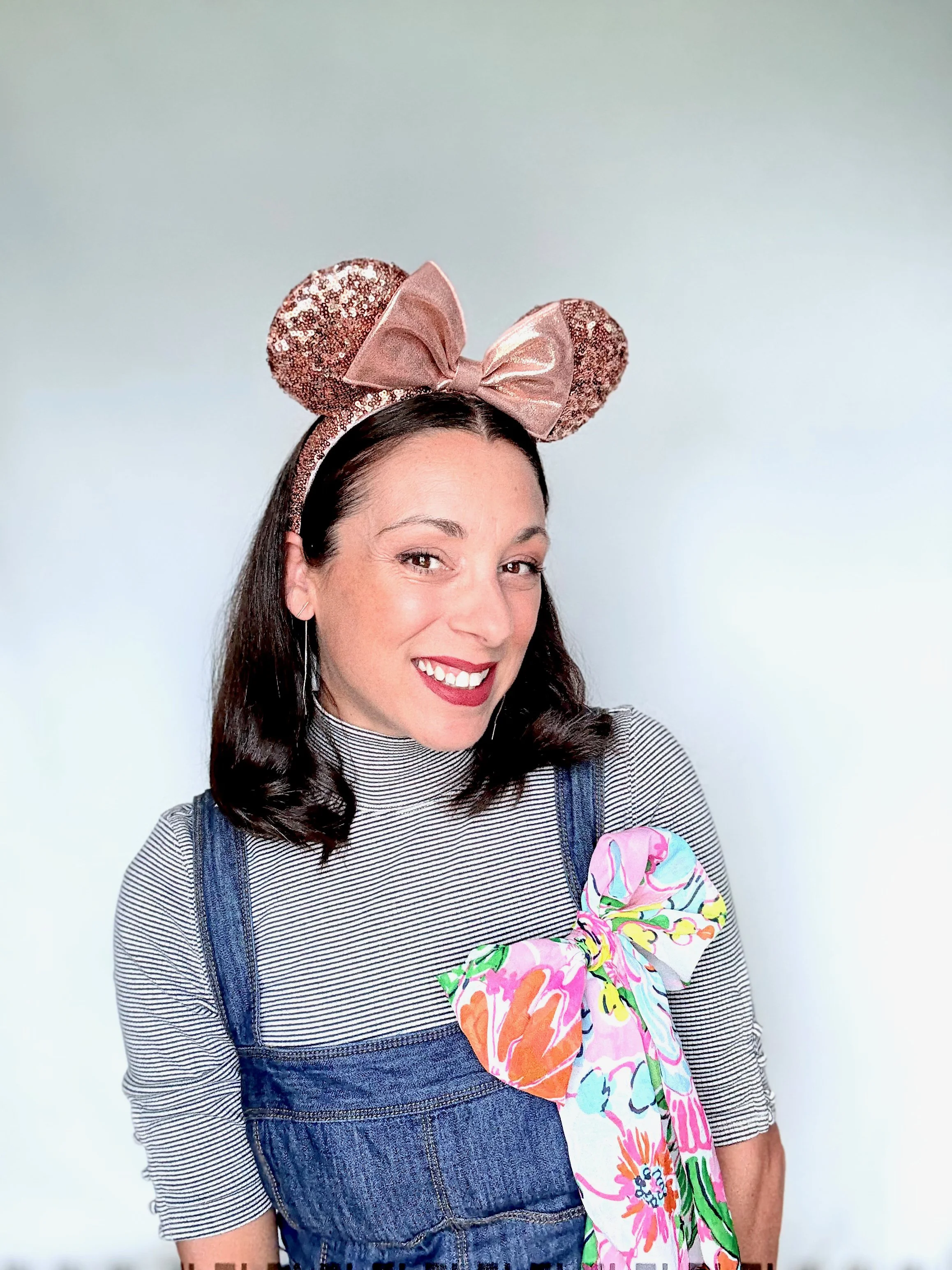Roberta wearing rose gold Minnie Mouse ears and is ready to help you book your perfect Disney vacation!