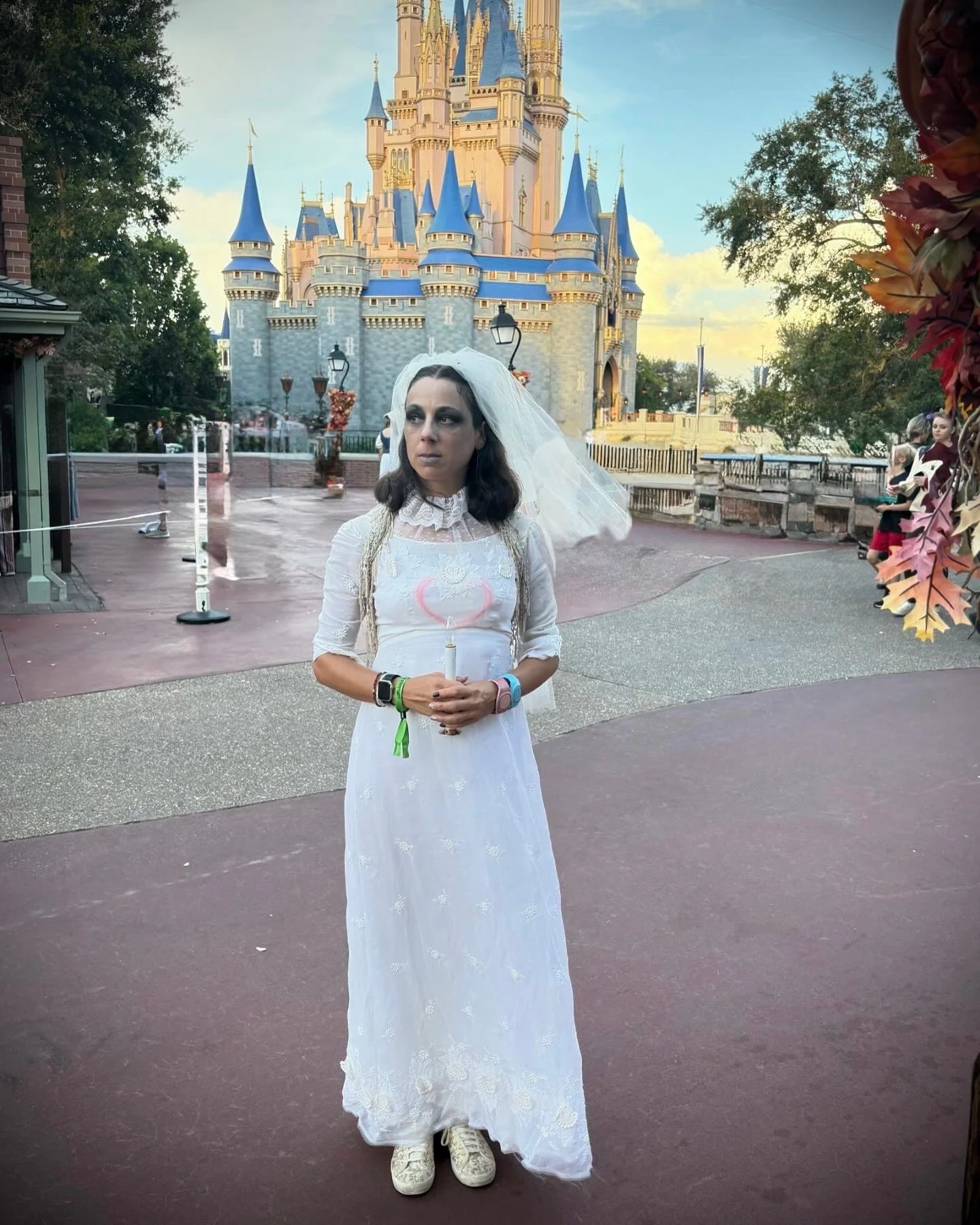 Roberta dressed as a bride from the Haunted Mansion, holding a candle standing in front of Cinderella's Castle at Disney World at the Mickey's Not So Scary Halloween Party