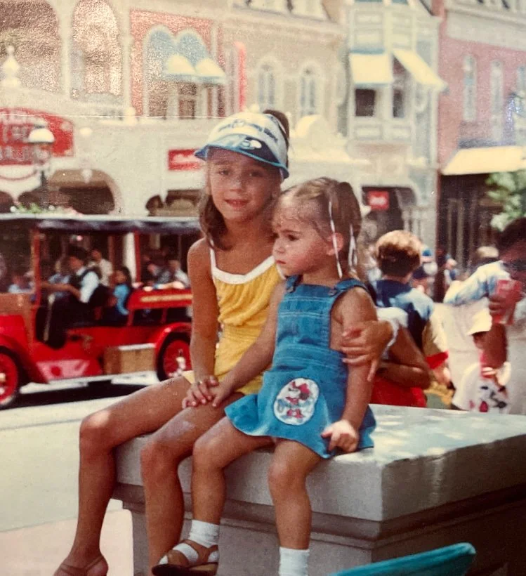 Roberta and her sister sitting on a stone ledge in Disney's Magic Kingdom