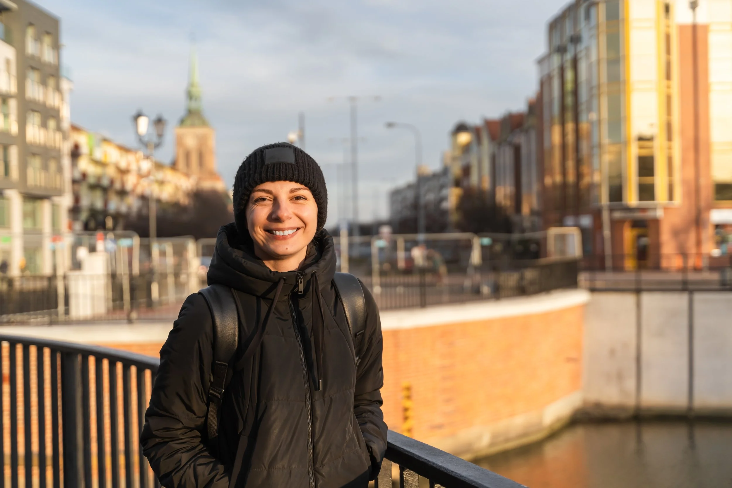 smiling-young-woman-traveling-with-black-backpack-happy-female-walking-city-street.jpg