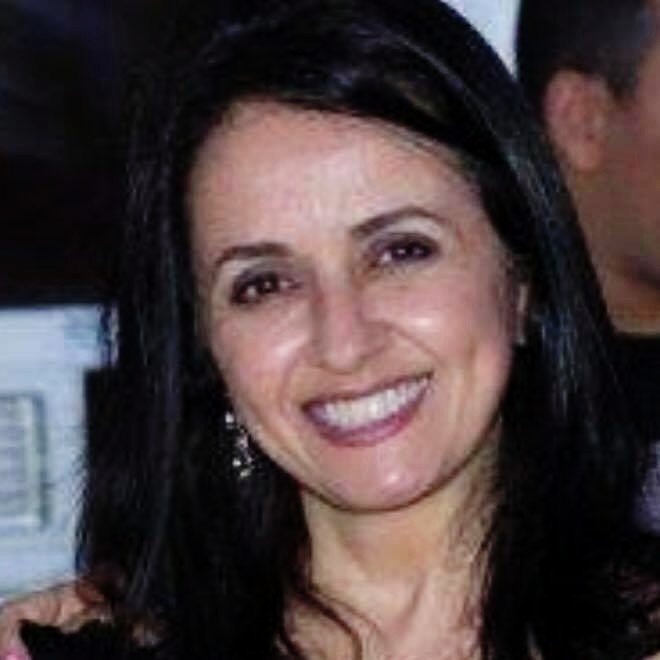 A woman with black hair smiling at a social gathering.