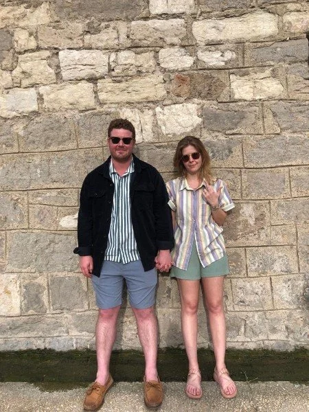 two people standing in front rock wall