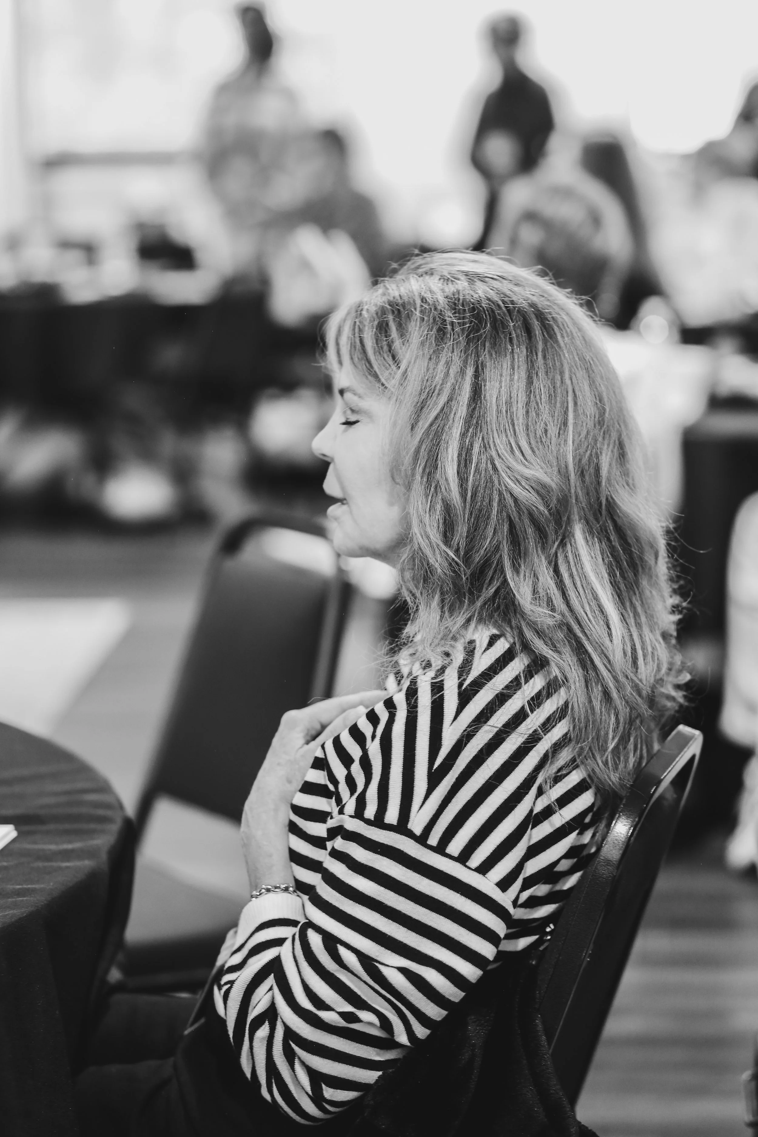 Woman in the audience at a Just Be Held retreat has her hand on her heart with her eyes closed