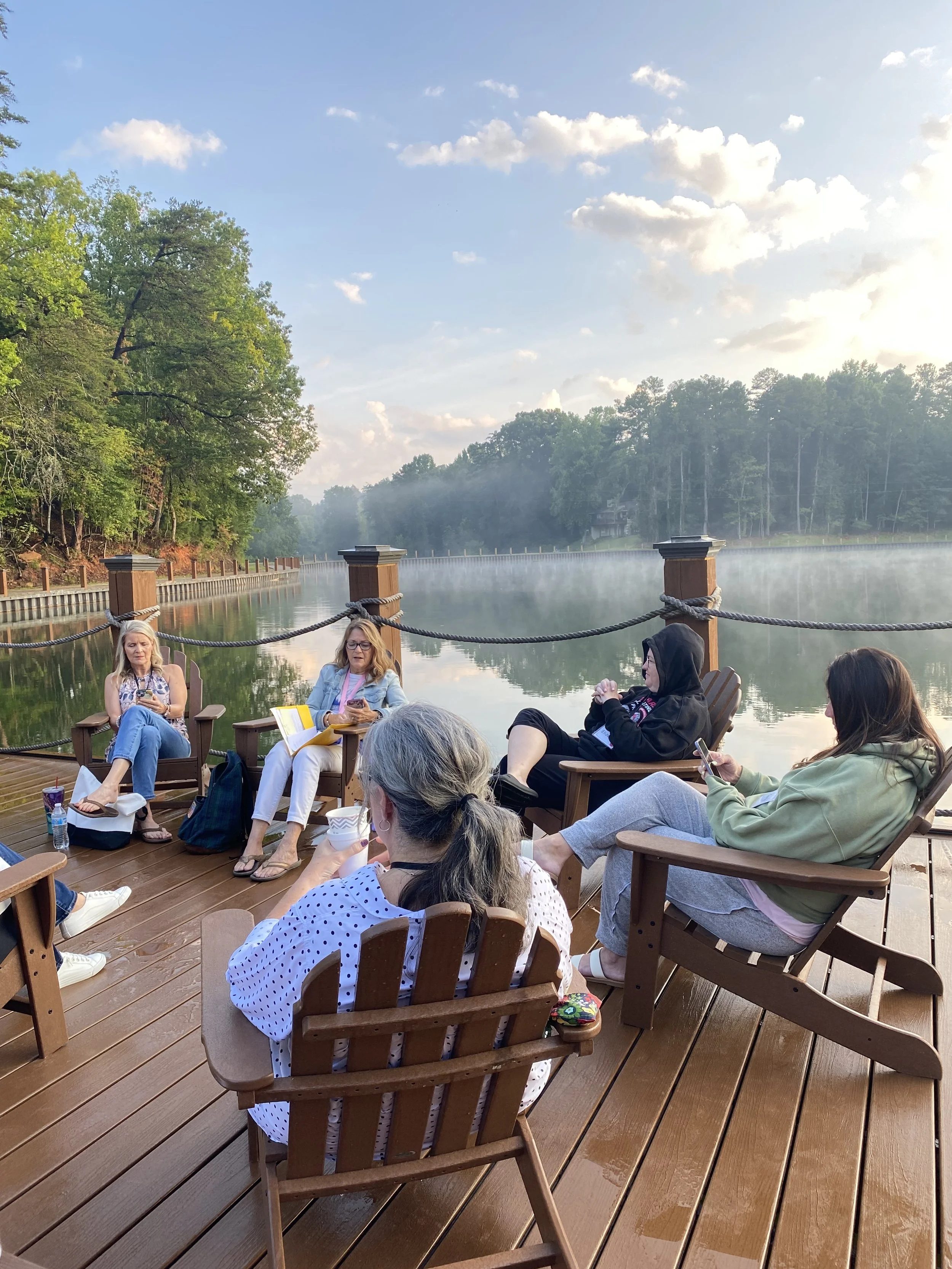 Women sitting in Adirondack chairs in front of the lake during a retreat