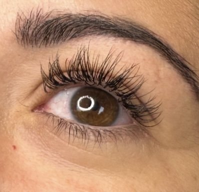 Close-up of a brown eye with long eyelashes and well-groomed eyebrow.