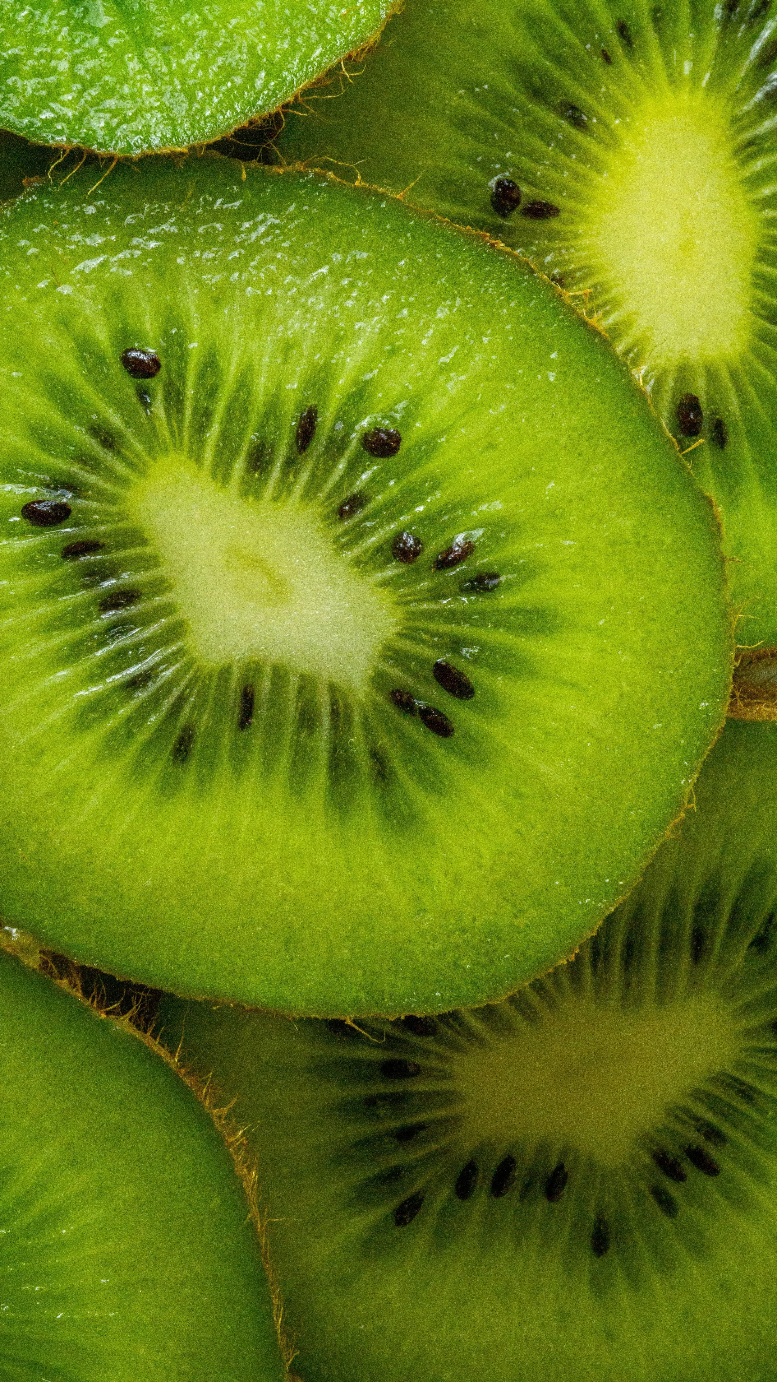 Close-up of sliced kiwi fruit showing green flesh, black seeds, and brown skin.