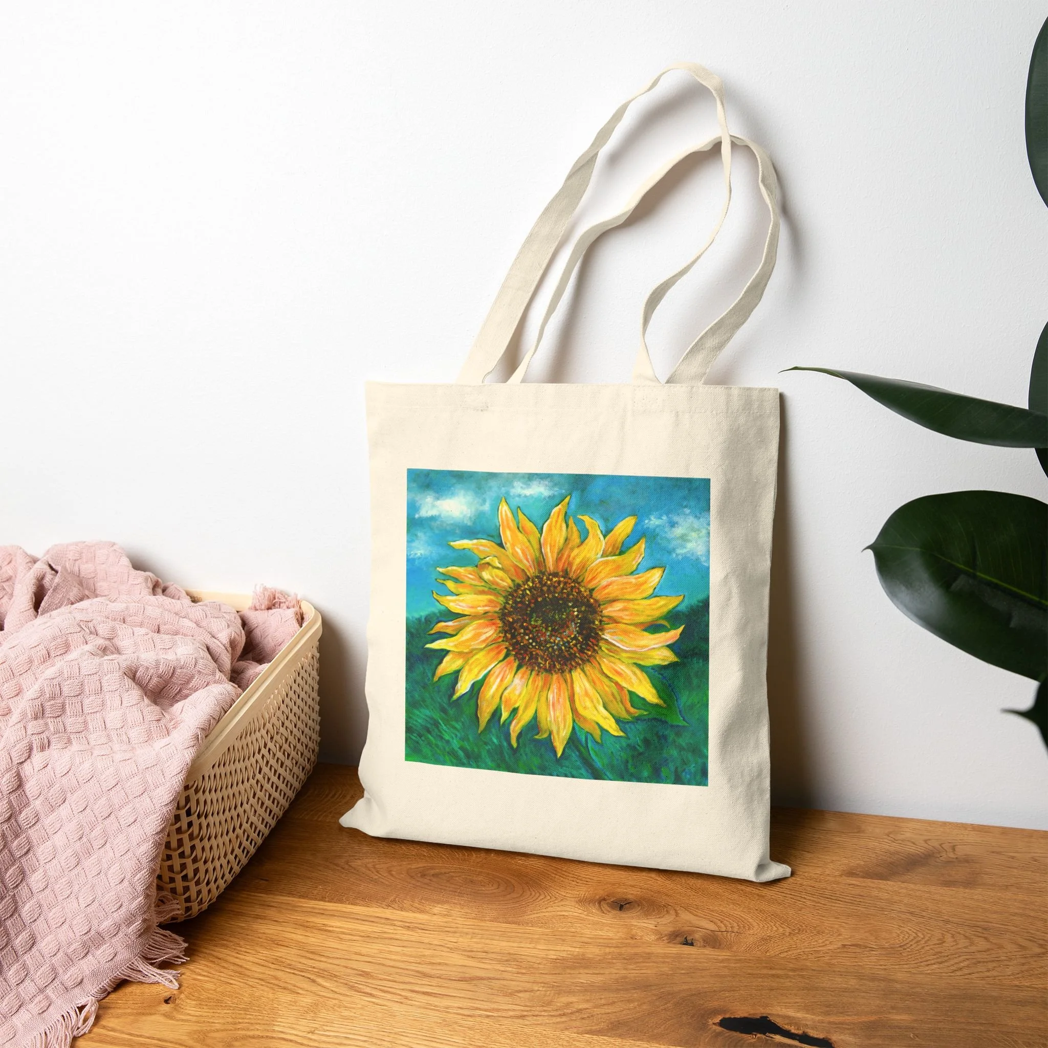 A beige tote bag with a sunflower painting on it.