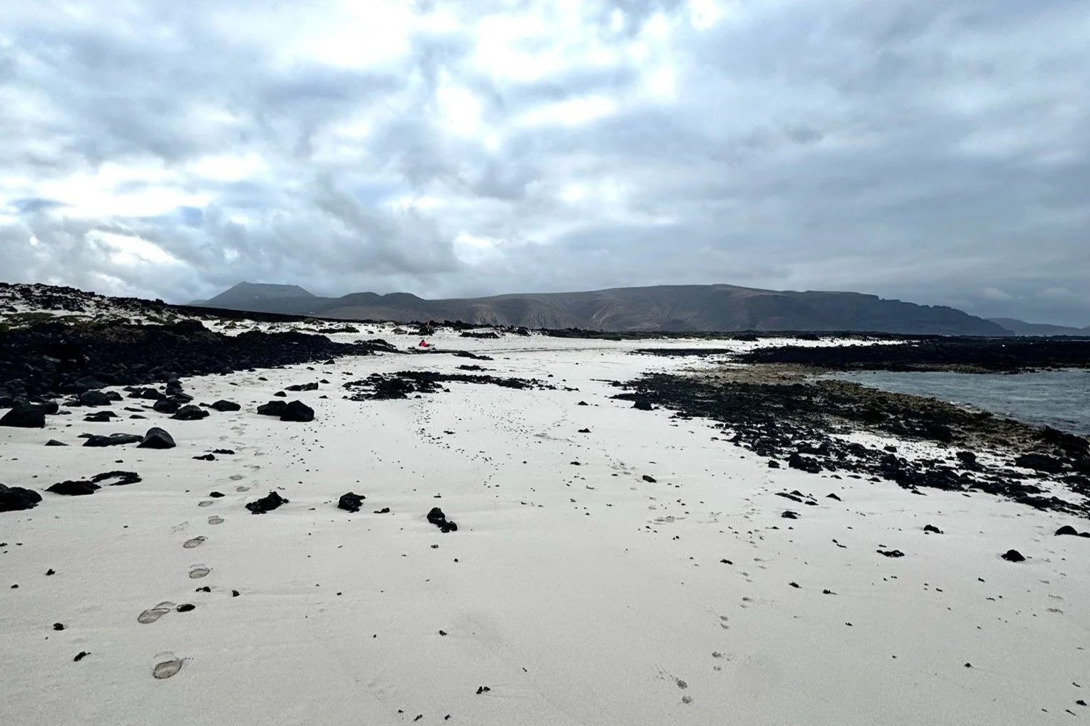 Quiet white-sand beach surrounded by black volcanic rock in northern Lanzarote.