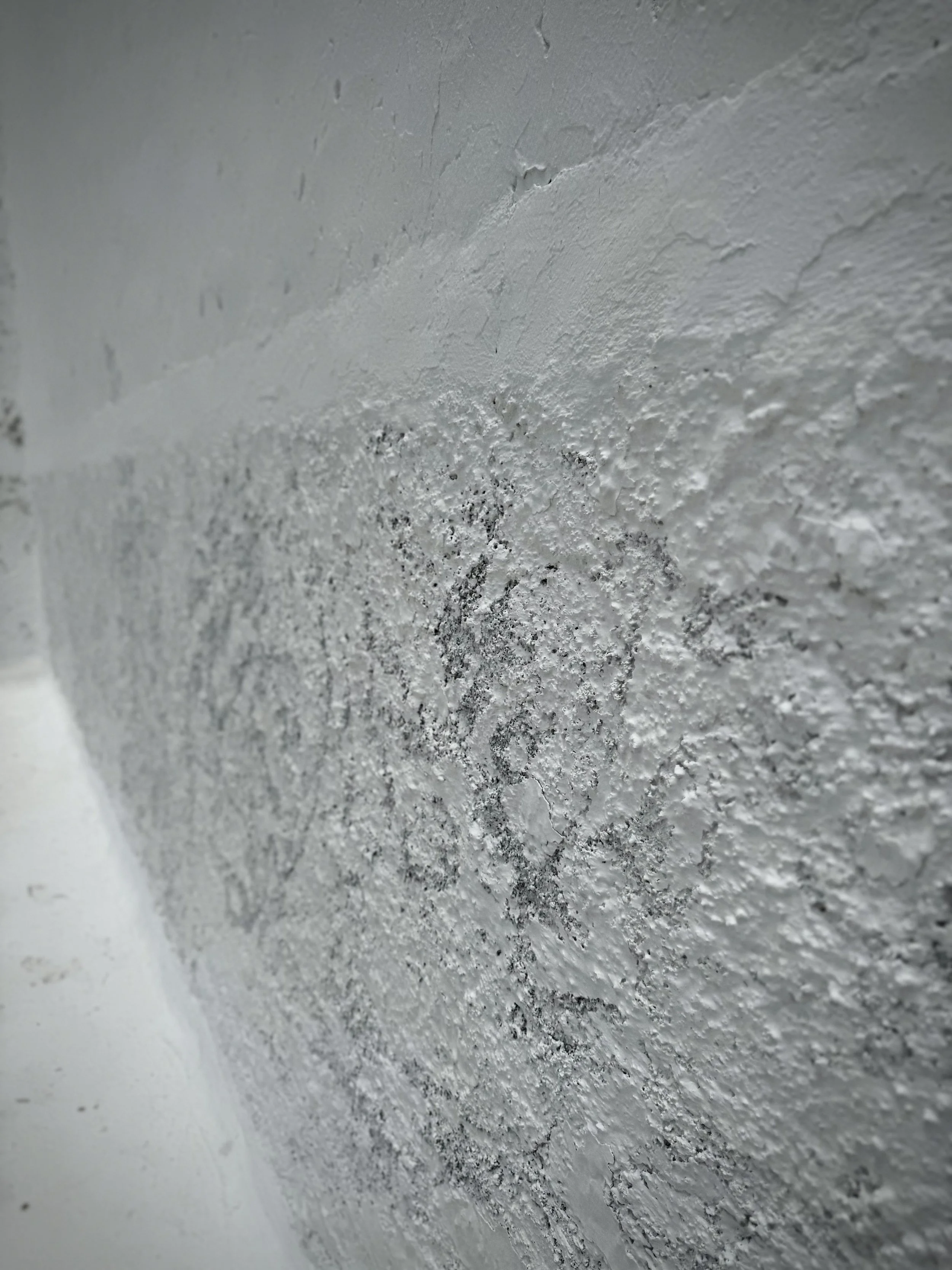 Weathered white plaster wall in Lanzarote revealing natural texture beneath the paint.