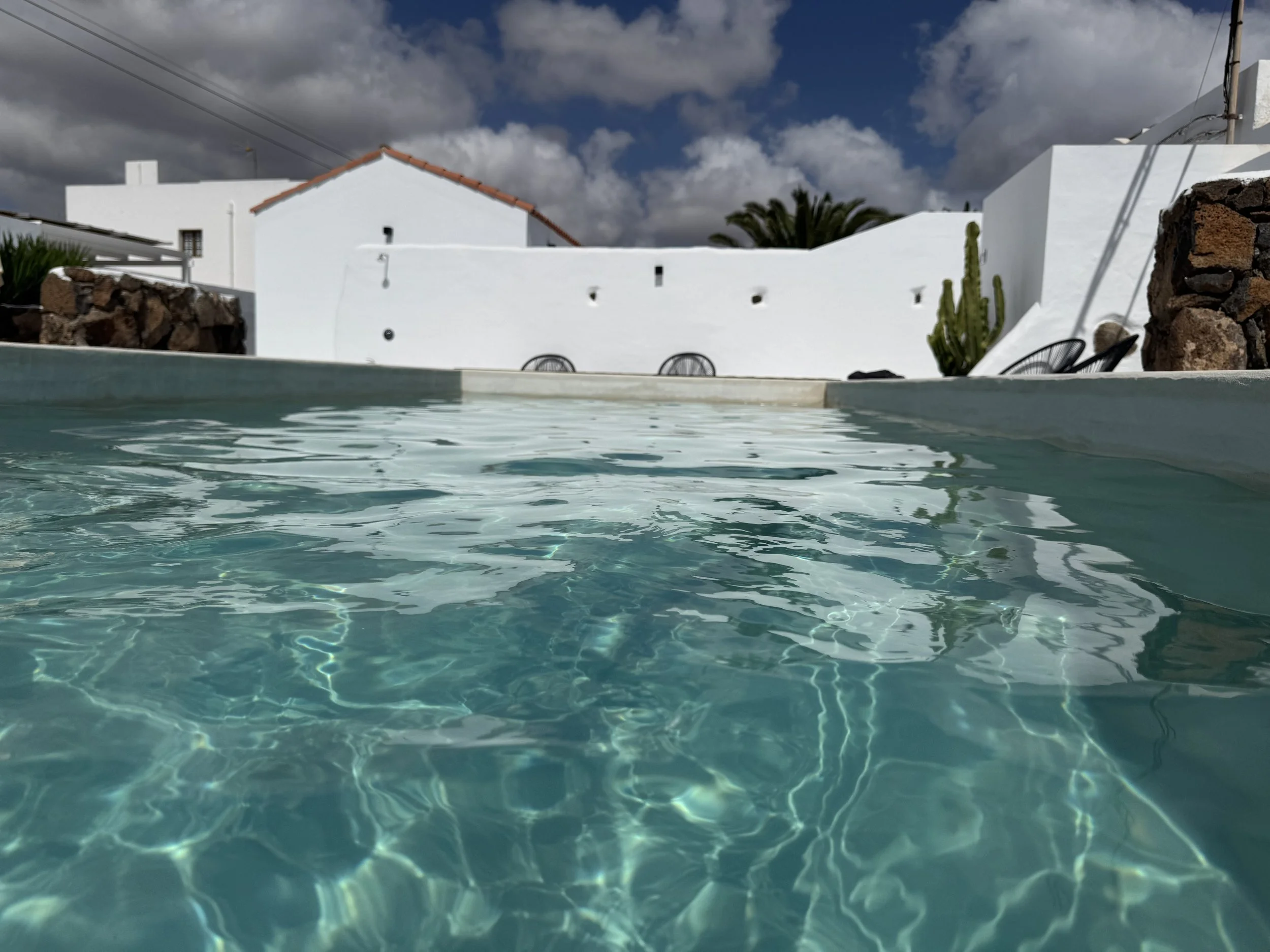 Piscina rodeada de jardín volcánico y arquitectura blanca en Casitas Santa Rita Lanzarote
