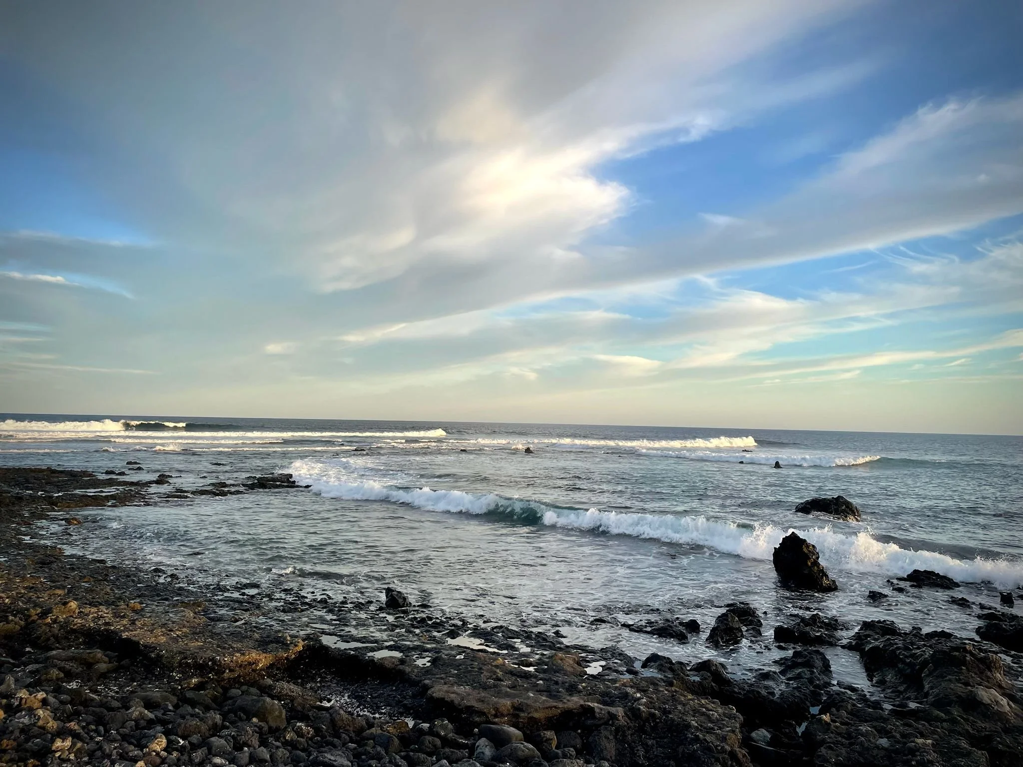 Rocky Atlantic coast of Lanzarote with ocean waves and a partly cloudy sky