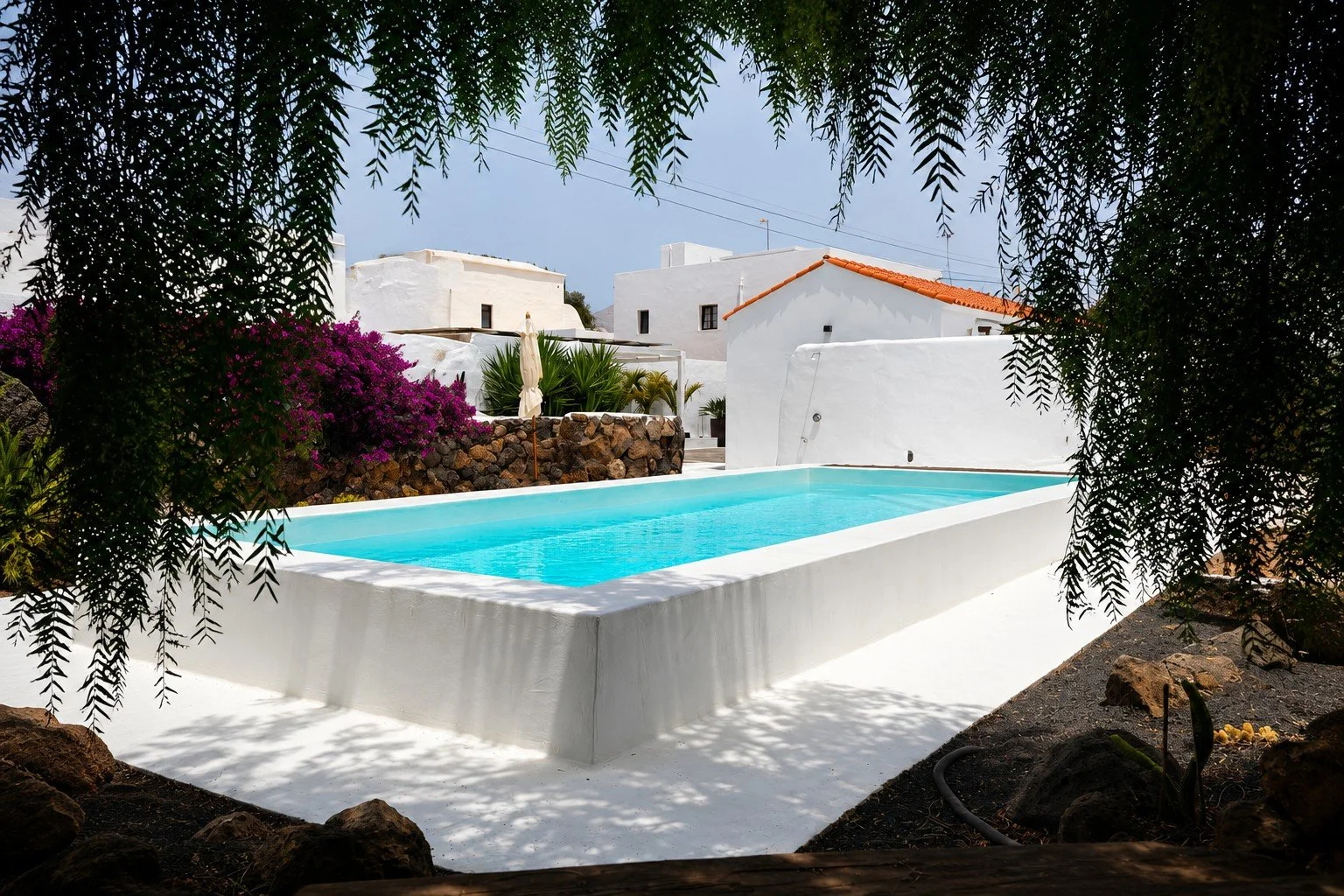 Heated pool with volcanic stone, cacti and white Canarian architecture at Casitas Santa Rita