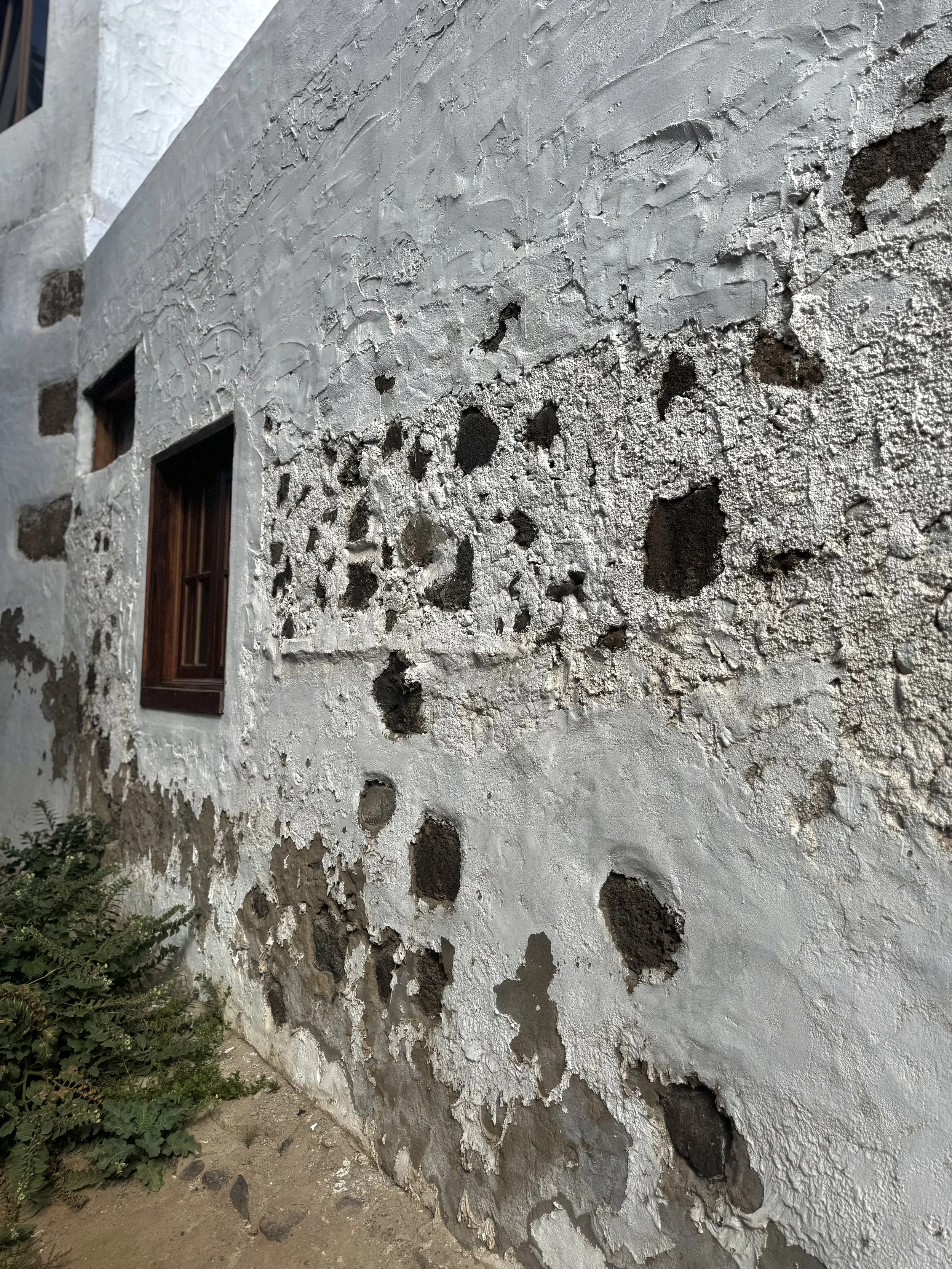 Old volcanic stone wall of a traditional house in Haria, Lanzarote showing natural ageing.