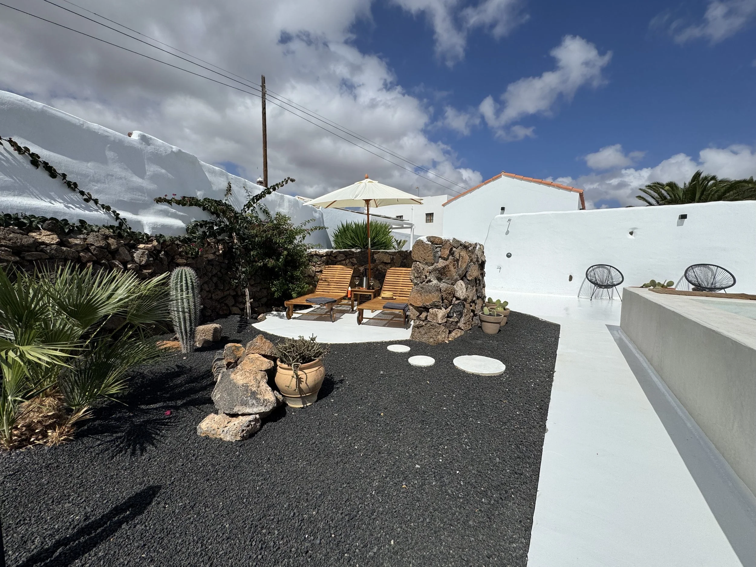 Swimming pool framed by volcanic landscaping and cacti in Lanzarote