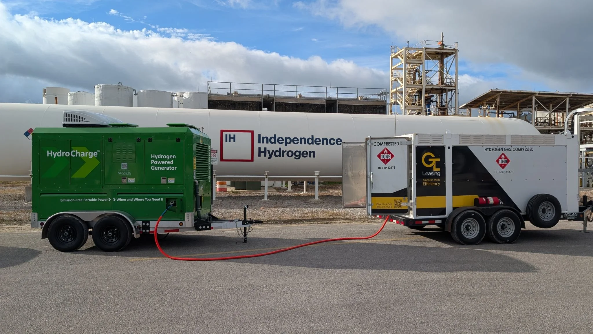 A portable hydrogen generator connected to a GTL Leasing hydrogen transport trailer in front of large storage tank labeled 'Independence Hydrogen' at an industrial facility.