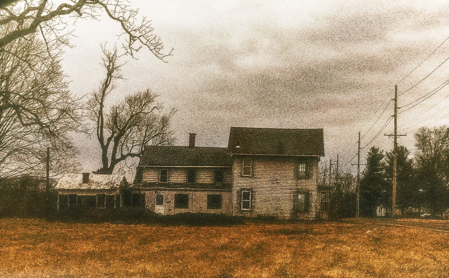 An old, abandoned house with peeling paint and broken windows, surrounded by leafless trees, under a dark, cloudy sky.
