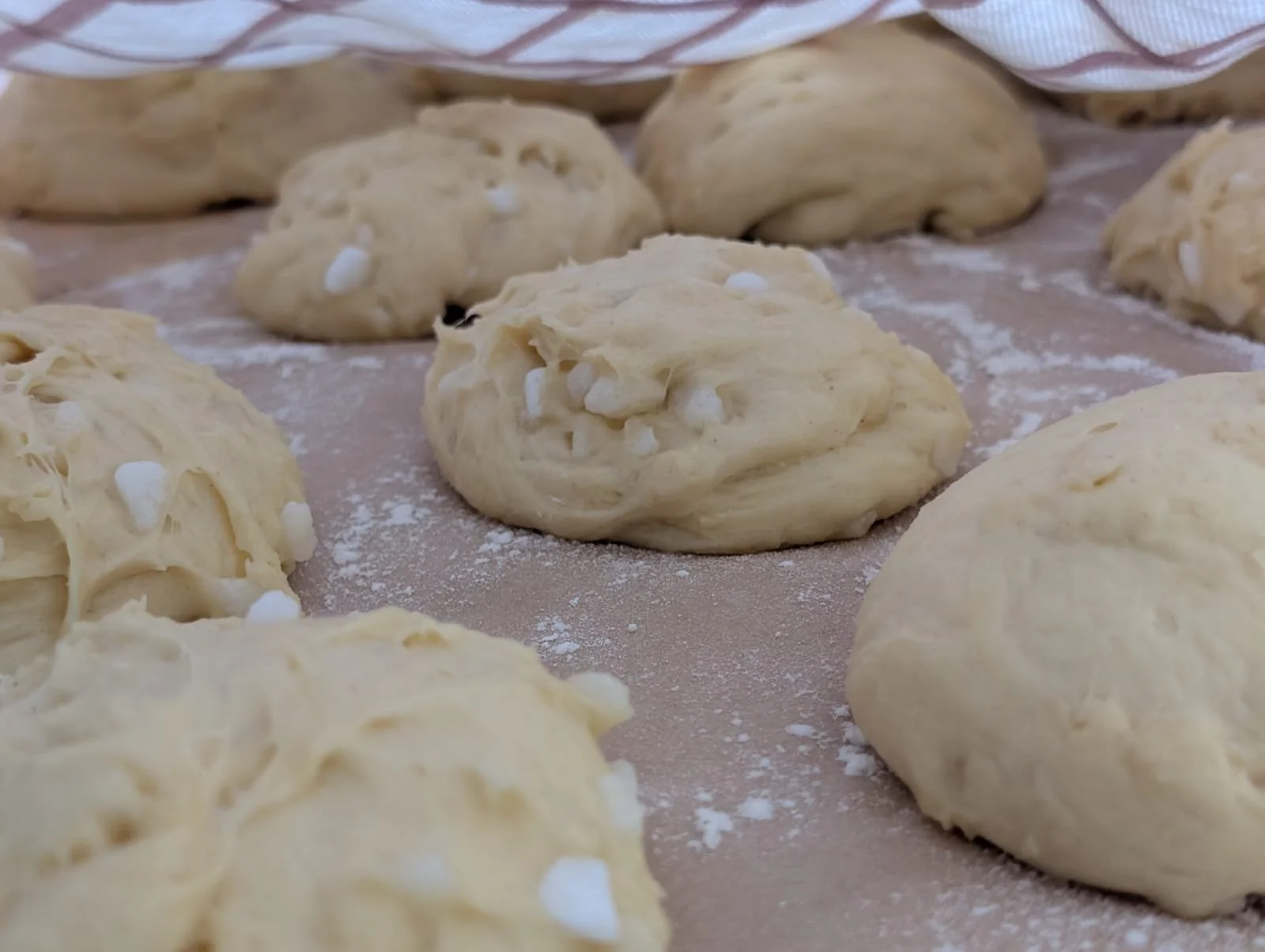 Close-up of dough balls on a floured surface prepared for baking.