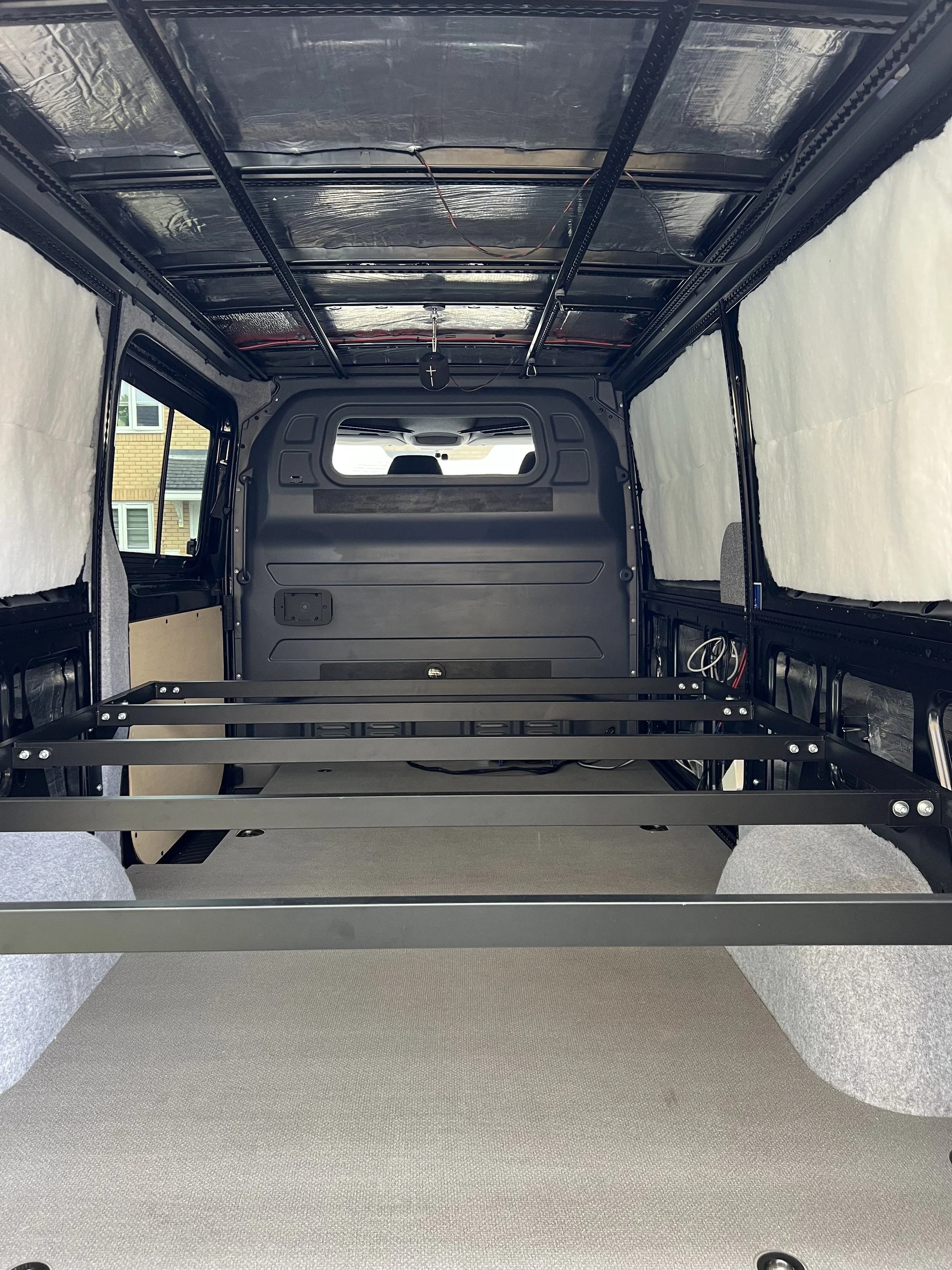 Interior of a vehicle's cargo area being prepared with metal frame and insulation.