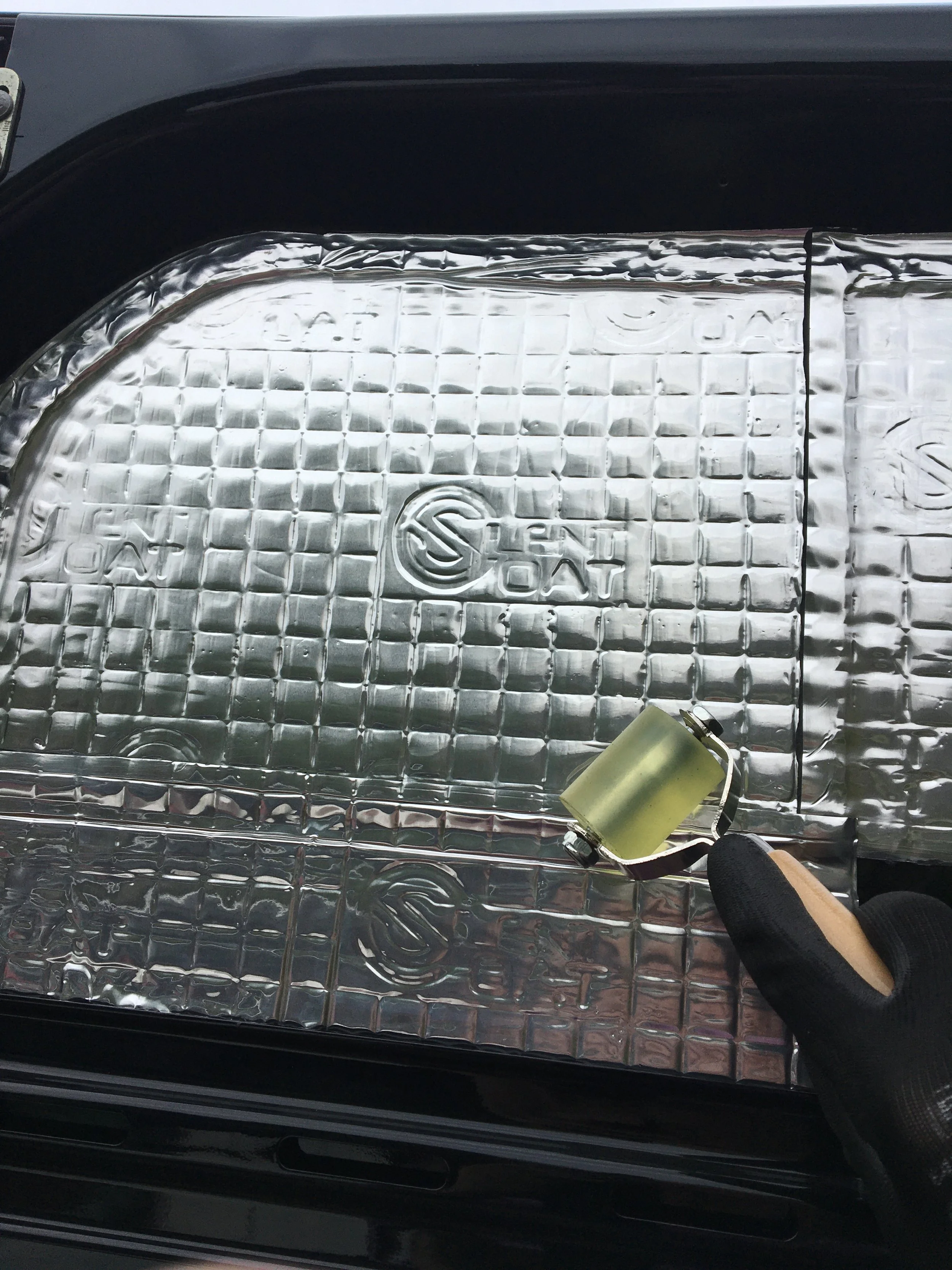 A car headlight with a reflective cover being held by a gloved hand.