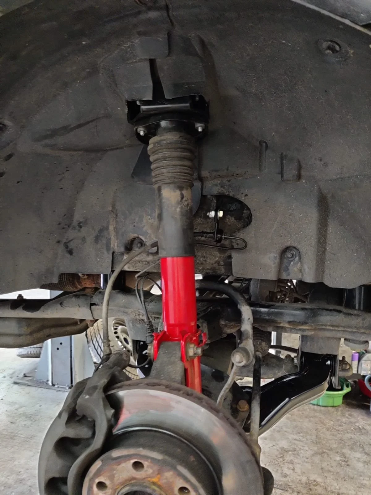 Close-up view of a vehicle suspension system showing the shock absorber, coil spring, and wheel hub assembly.