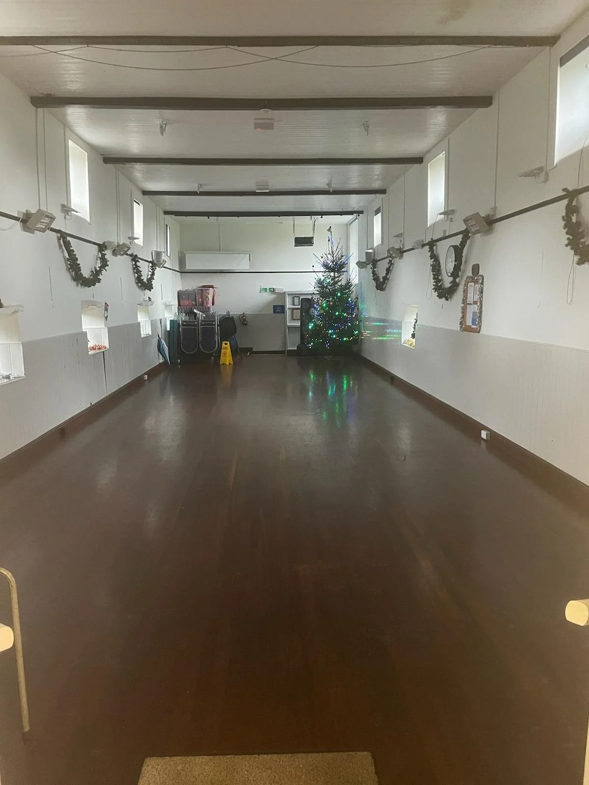 Empty room decorated for Christmas with a Christmas tree and holiday garlands.