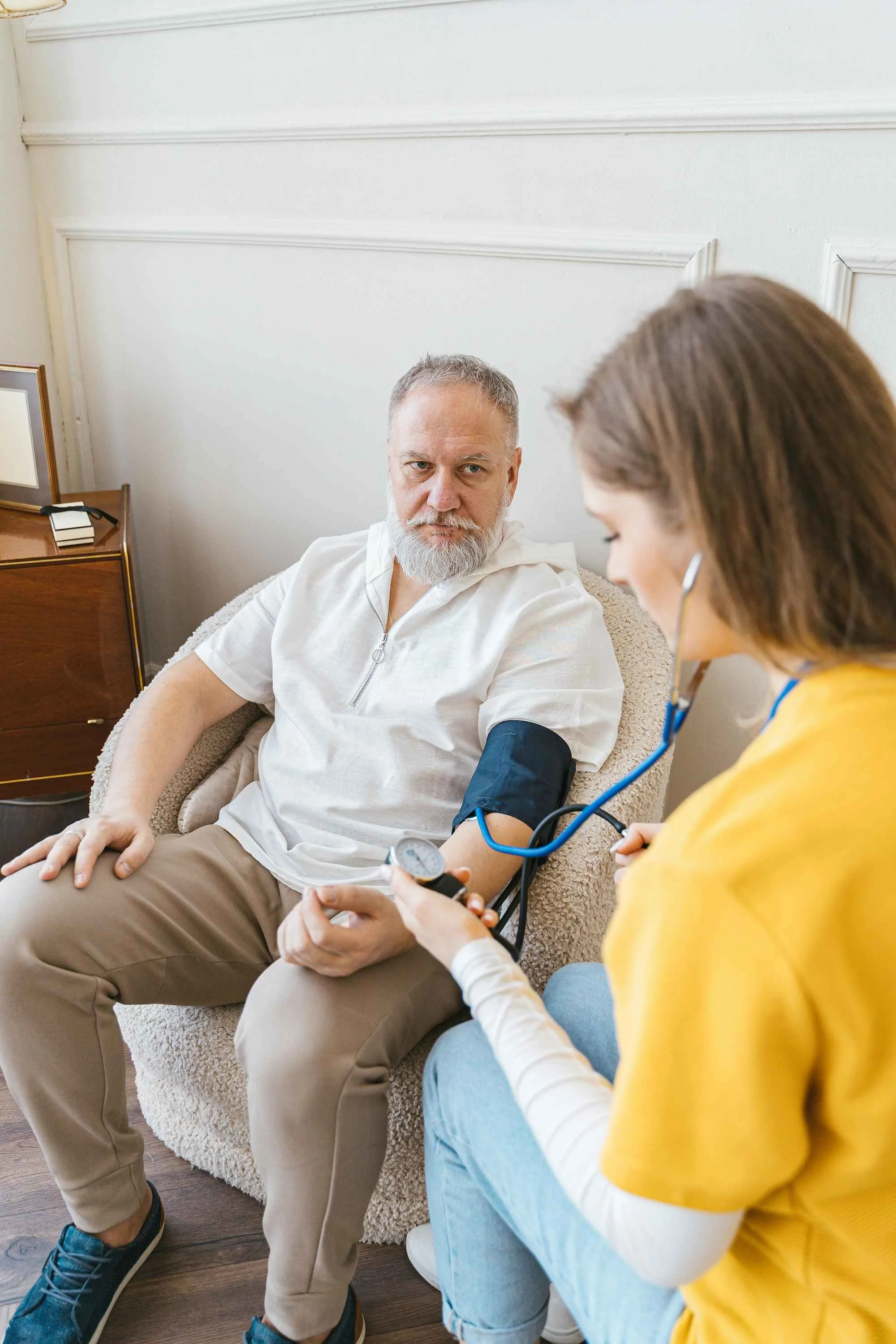 Caregiver assisting an elderly man during a routine wellness check at home