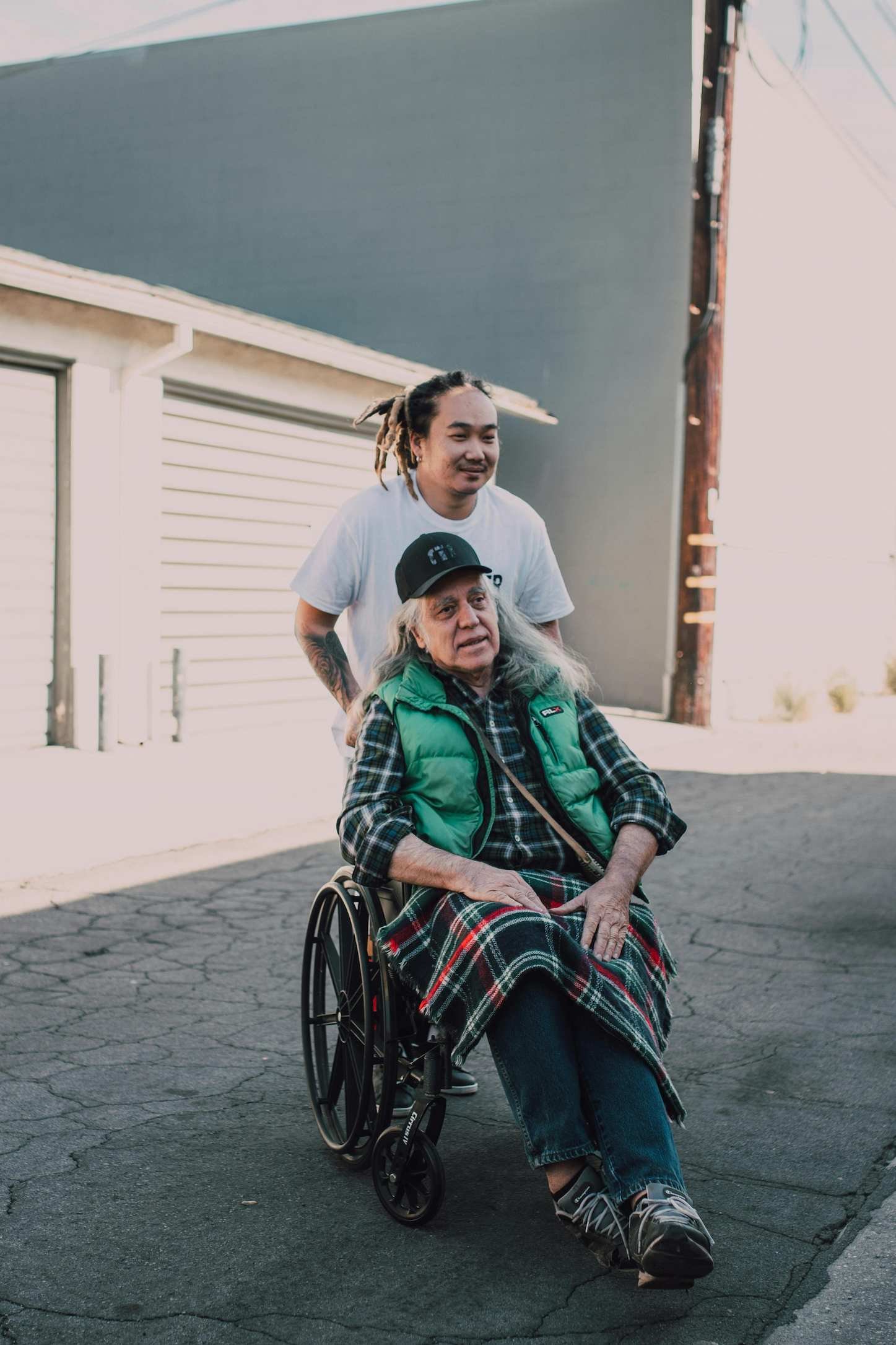 Male caregiver assisting an elderly man in a wheelchair in a home care setting