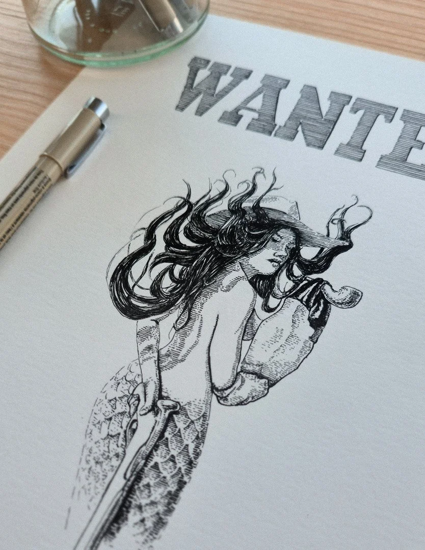 Photograph detail “WANTED – Original Illustration” by Daniel Perez Cabrera: ink illustration on workspace showing mythological figure reinterpreted in Western Wanted poster style.