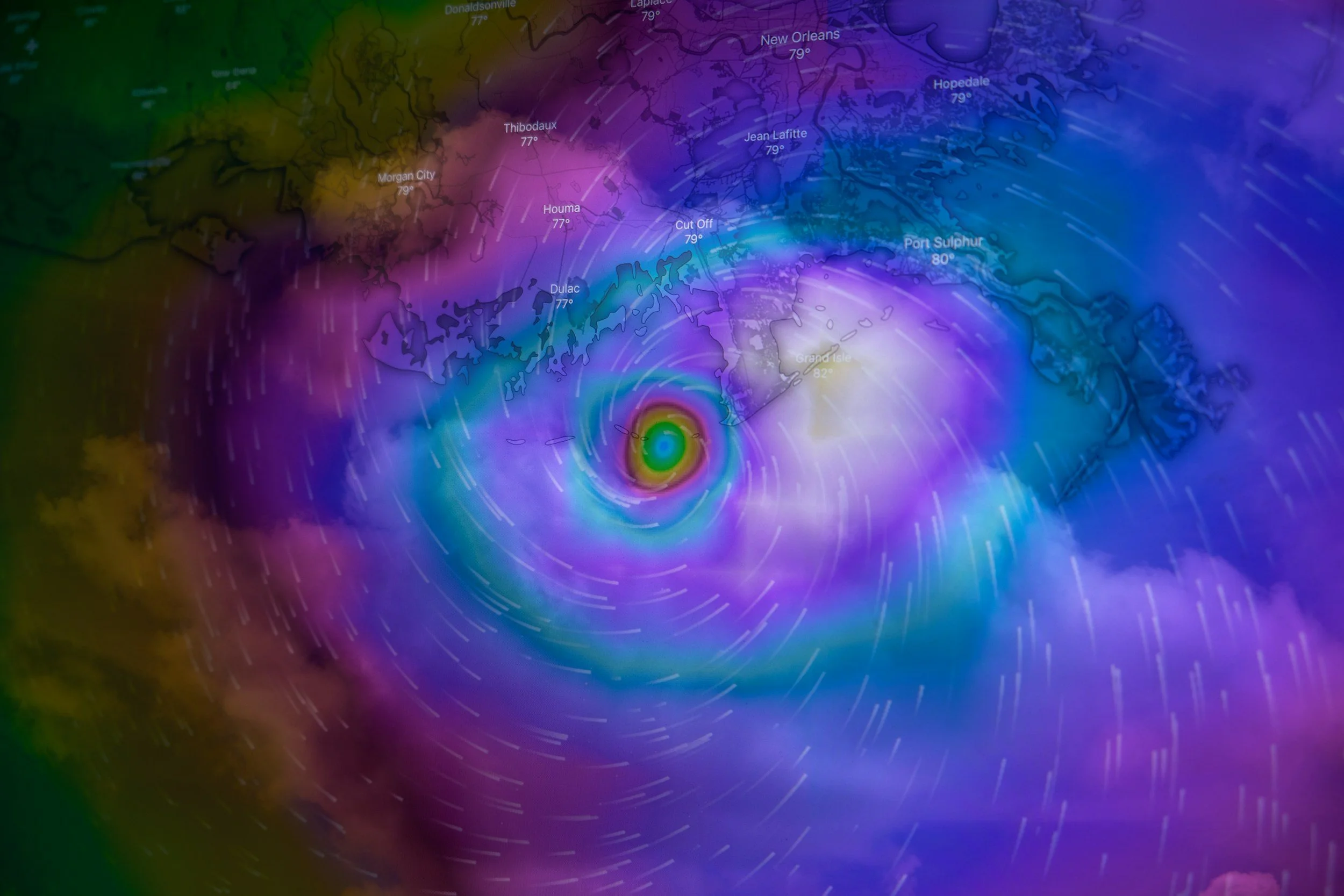 Hurricane approaching the Gulf Coast, with swirling cloud patterns and wind streams over Louisiana and Mississippi, annotated with city names and temperatures.