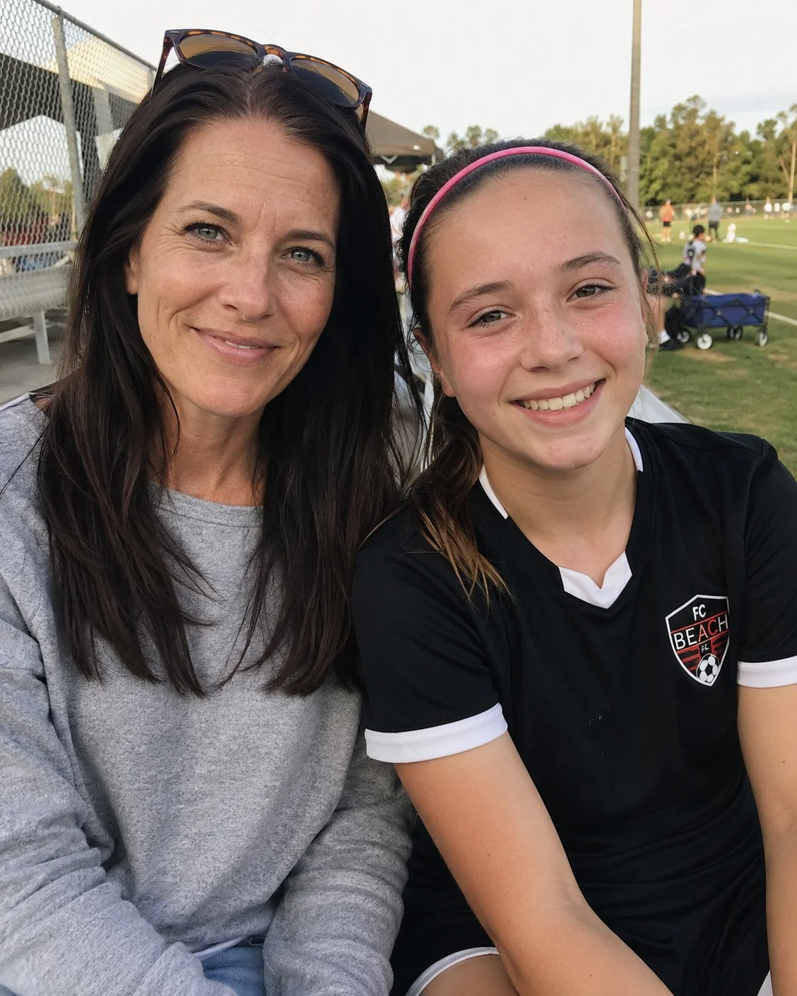 Mother and young soccer player smiling together on the sidelines at a youth soccer game