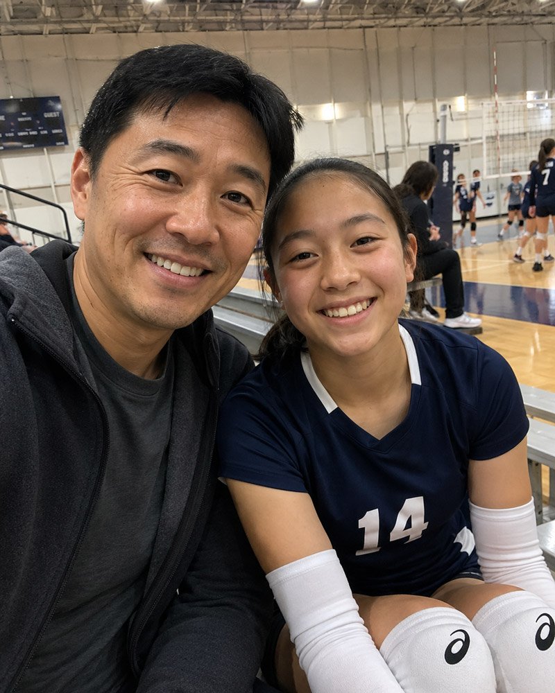 Father and teenage volleyball player smiling together in a gym during a youth volleyball game