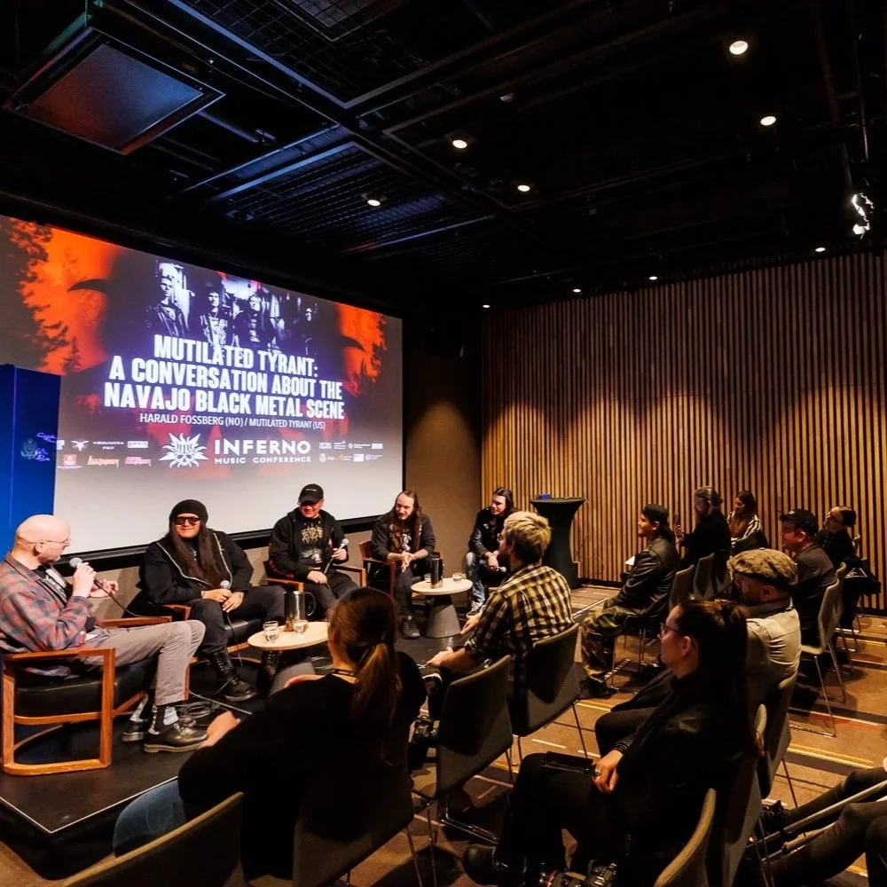 Panel discussion at Infraero Music Conference on the Navajo Black Metal scene, with four panelists on stage and seated audience members.