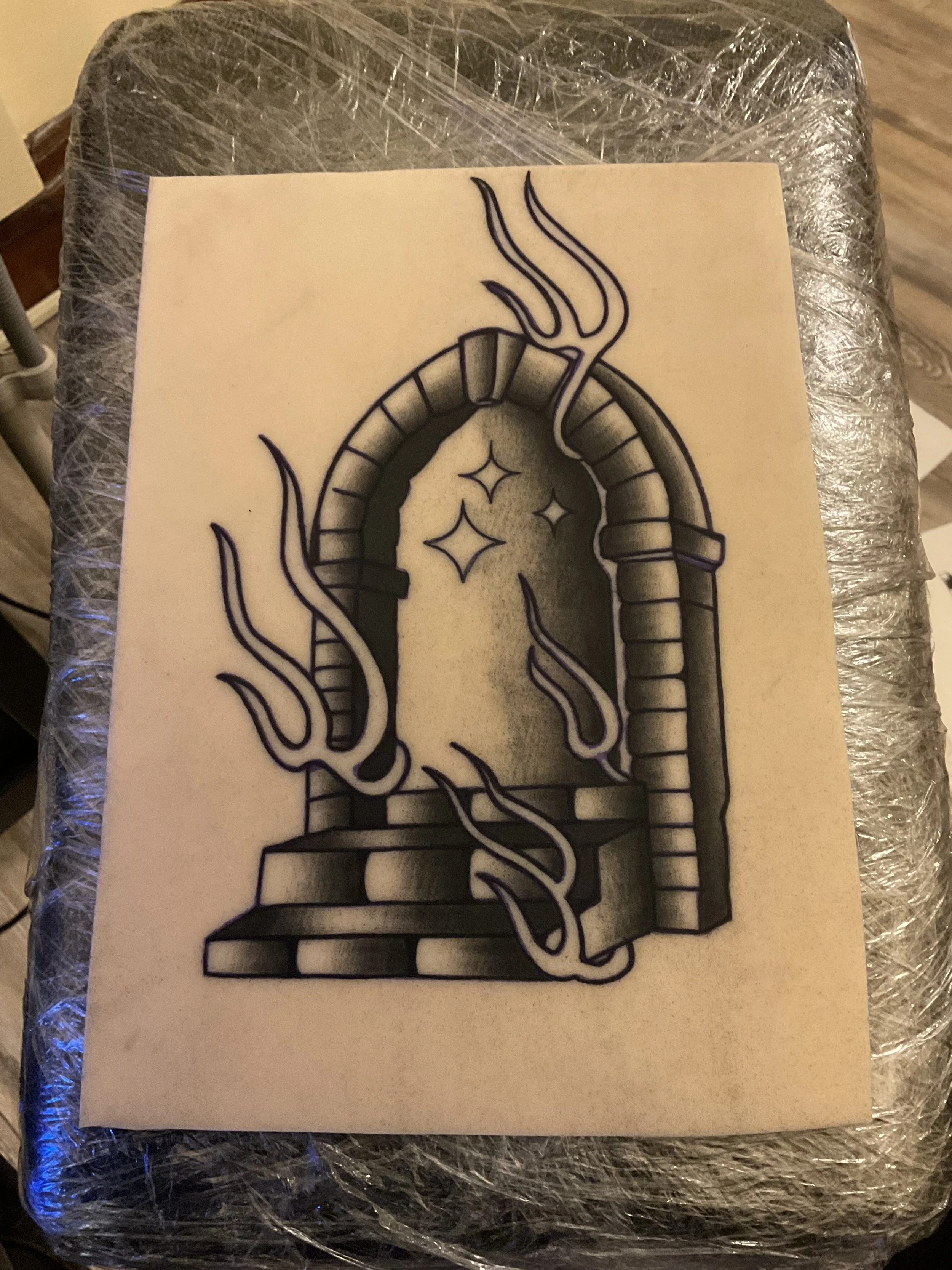 Black and white tattoo design of a stone archway with stars inside, surrounded by smoke or steam.