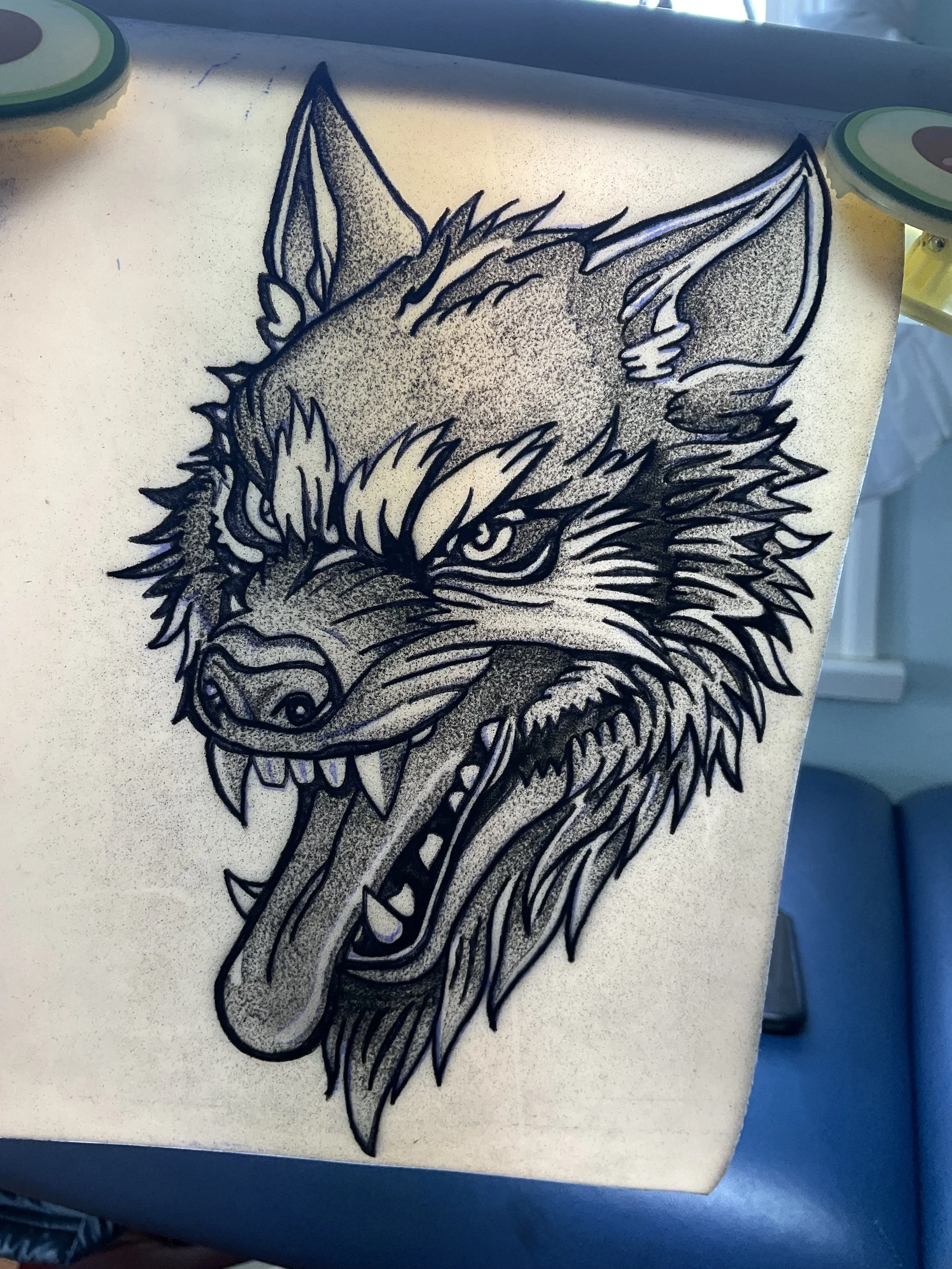 Black and gray illustration of an angry wolf's head with bared teeth and piercing eyes, on a white background.