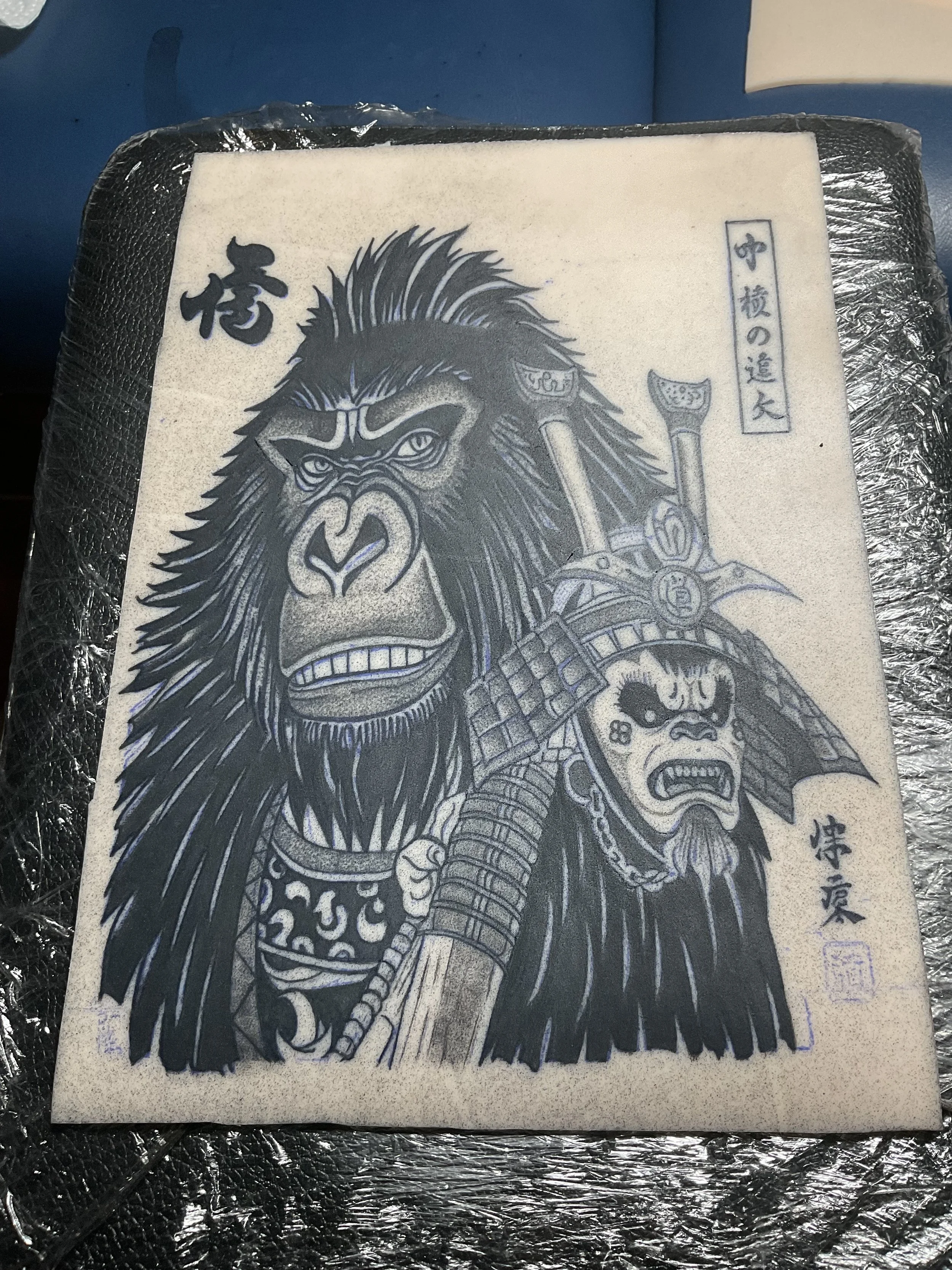 A black and white illustration of a fierce gorilla and a traditional tribal warrior with a headdress, swords, and armor on a textured background.
