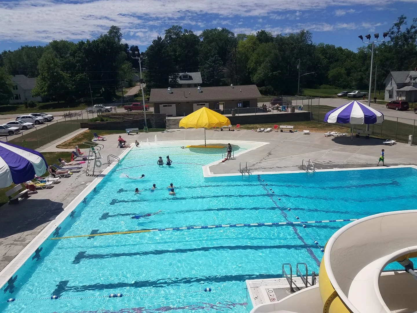 swimming pool with slide, brightly colored umbrellas and a bath house