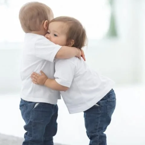 Two young children hugging each other.